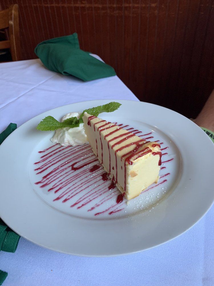 A white plate topped with a slice of cheesecake