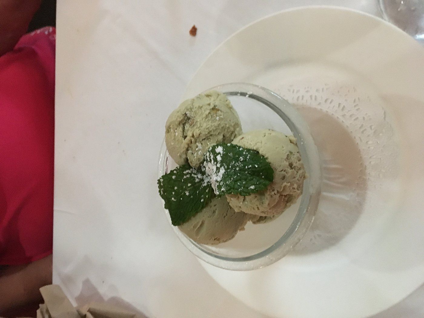 A white plate topped with three scoops of ice cream and mint leaves.