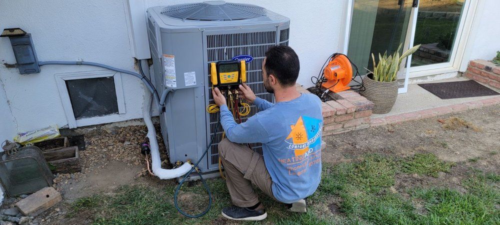 A man is working on an air conditioner outside of a house.