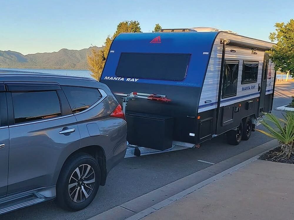 A Car Is Towing A Trailer Down A Street — Lake Macquarie Caravan Repairs In Cardiff, NSW