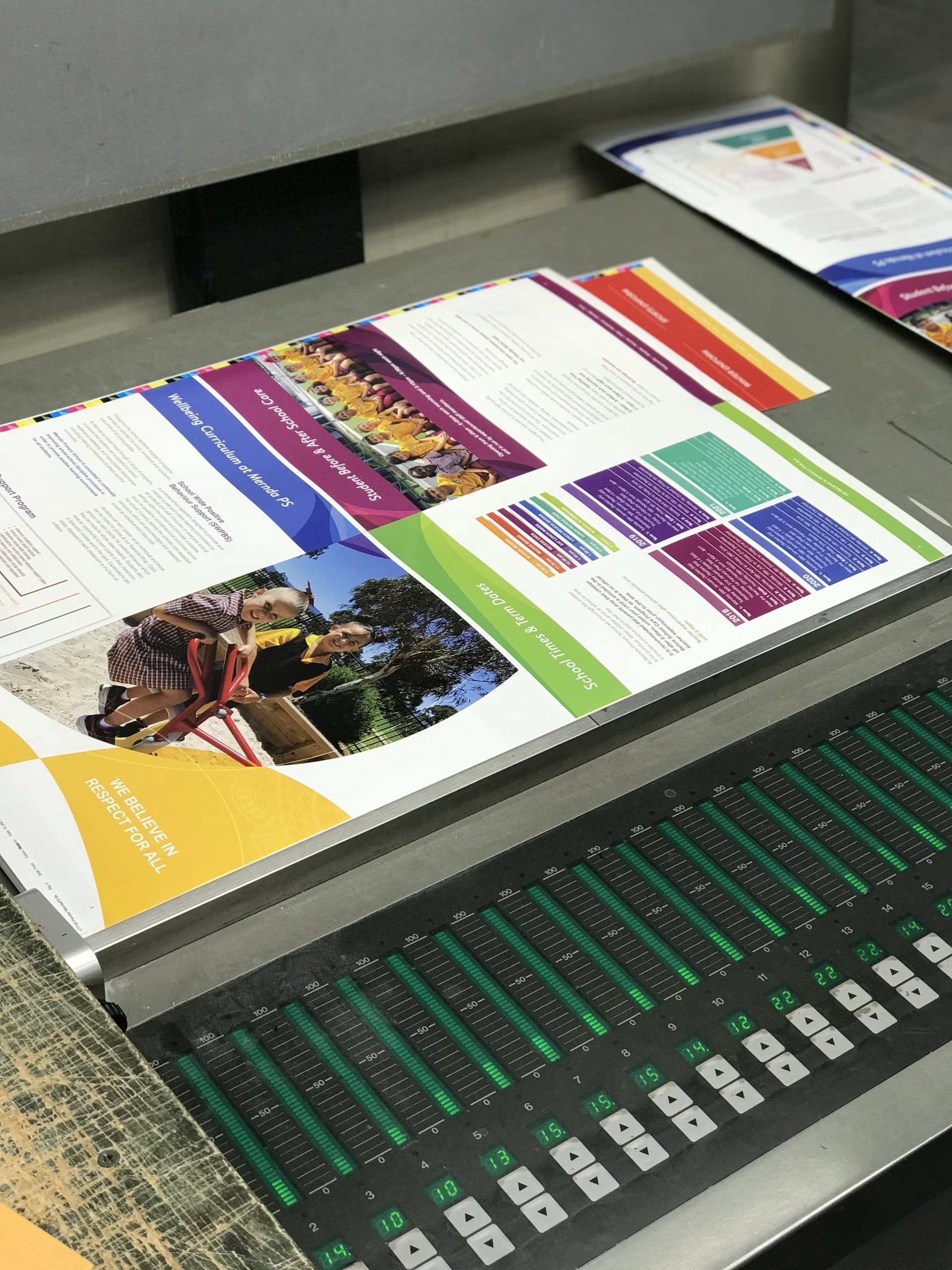Printed brochures on a printing press, showcasing colorful layouts.
