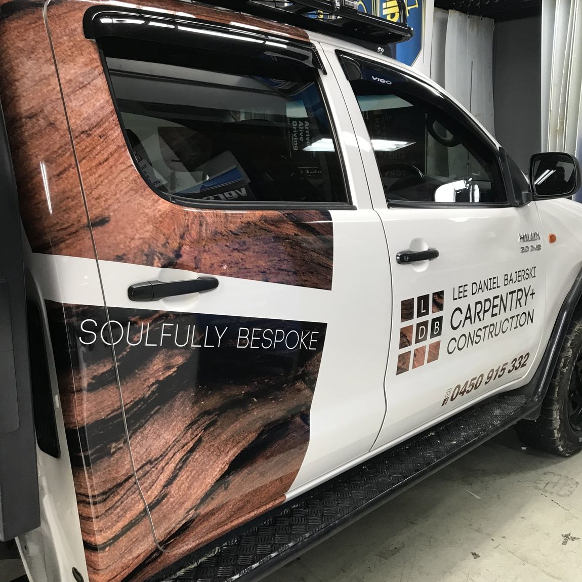 White pickup truck with wood grain wrap, company logo, and 