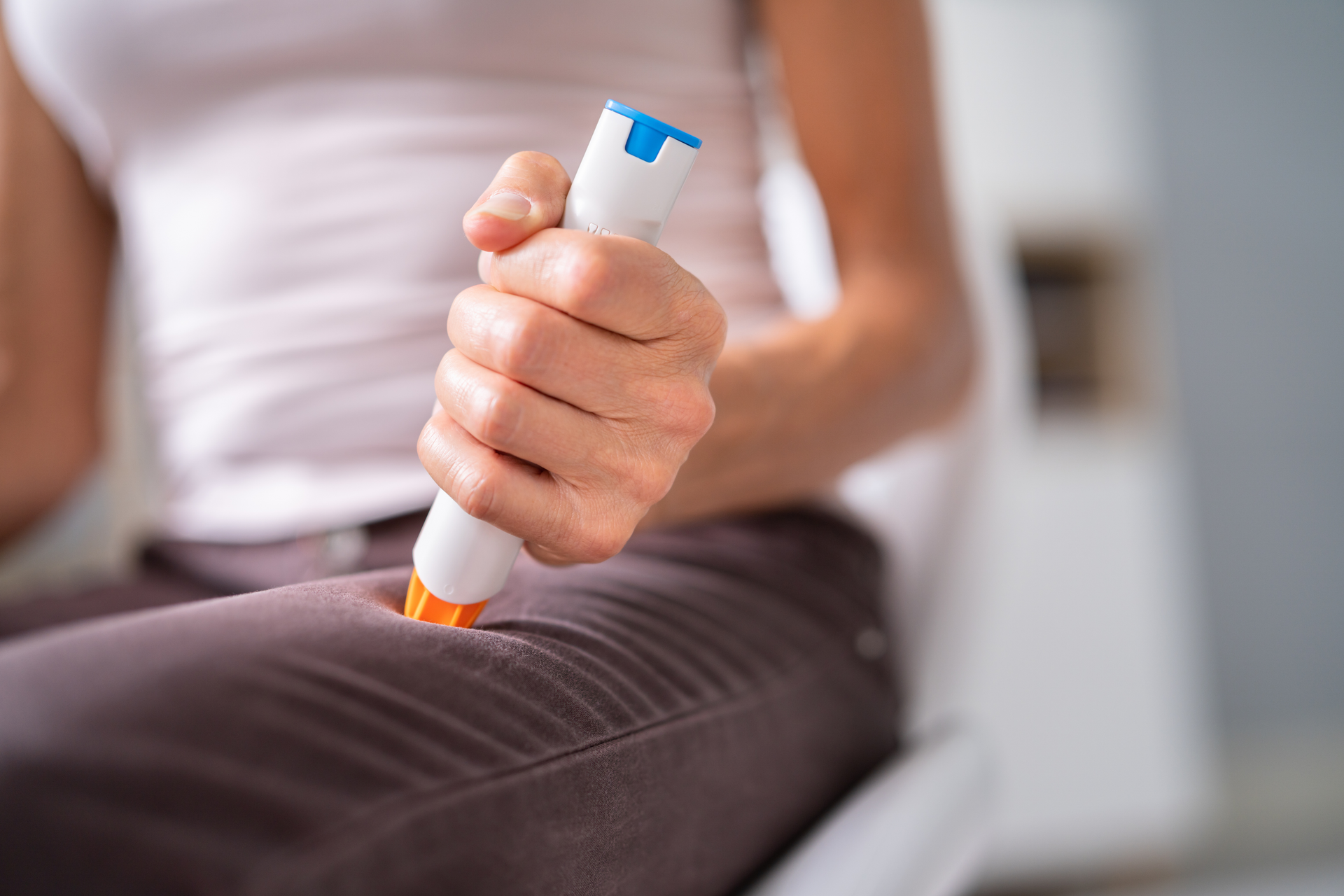 A woman is sitting on a chair holding a syringe in her hand.