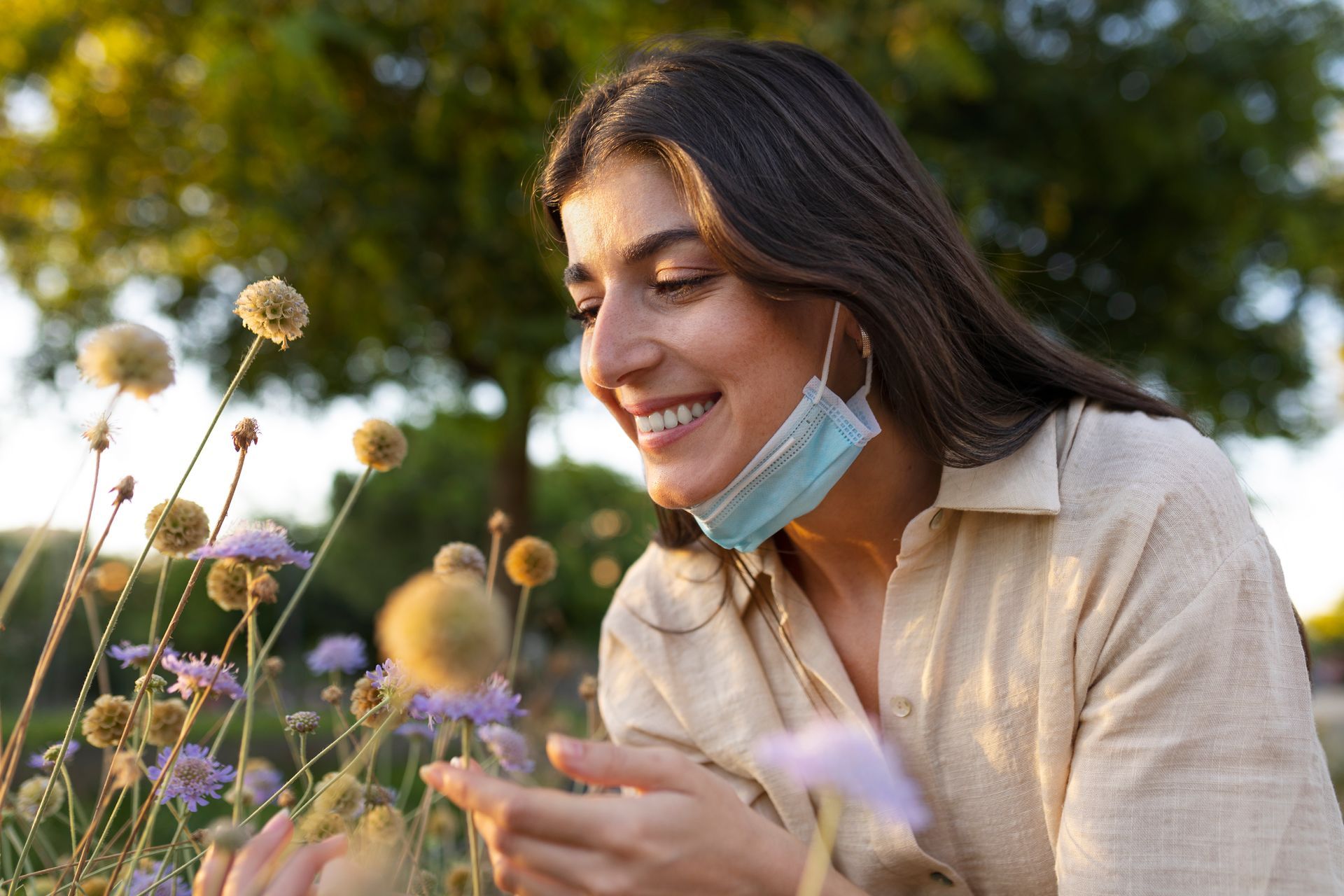 A woman smiling at flowers, no longer bothered by her allergies.