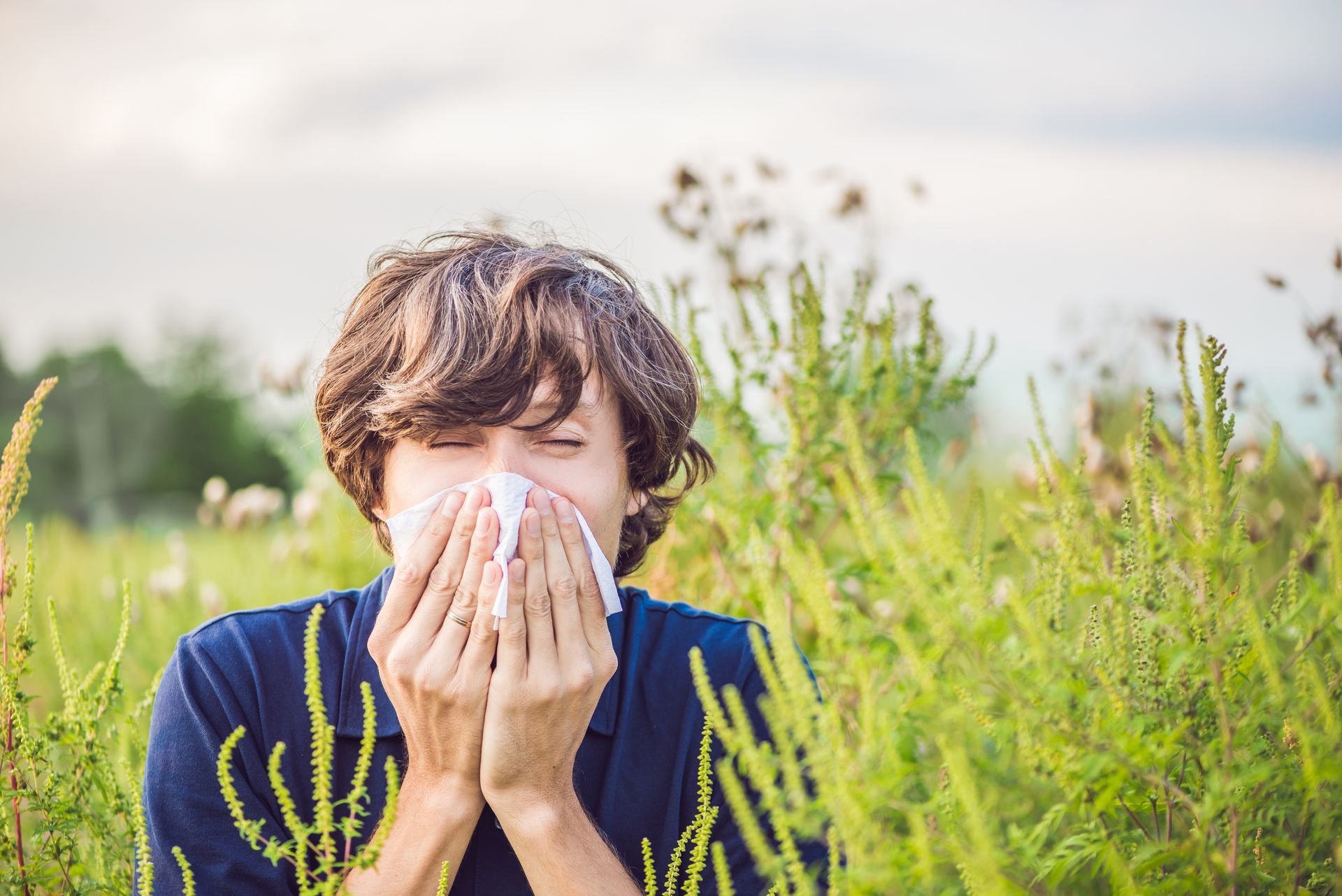 A man sneezes because of an allergic reaction to ragweed season