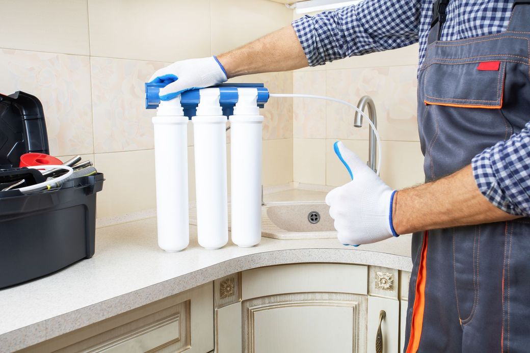 Un uomo sta pulendo un filtro dell'acqua in cucina.