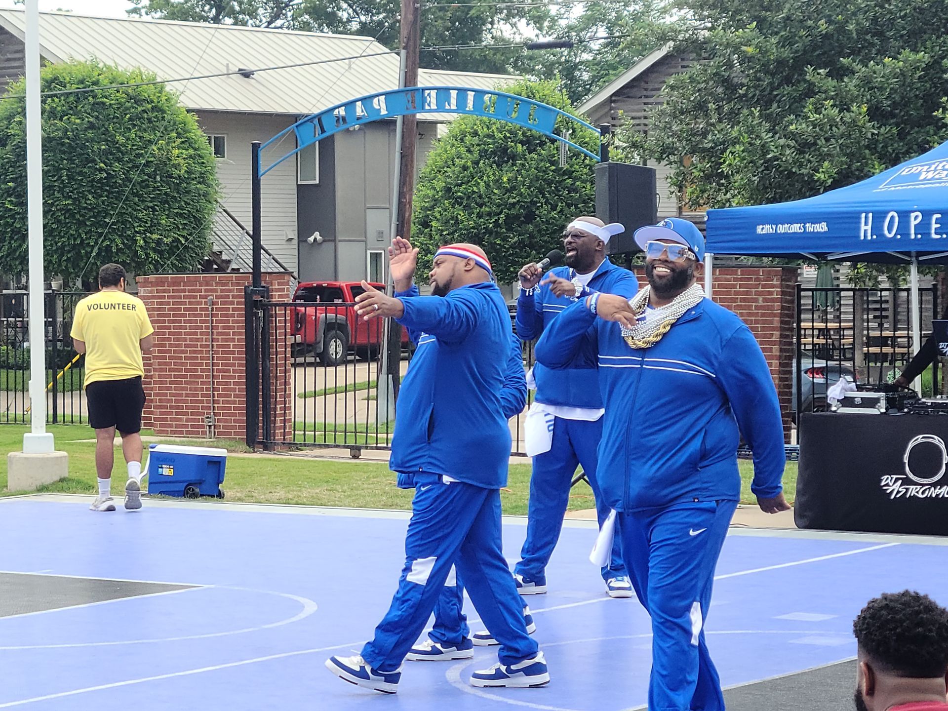 A group of men in blue jackets are walking on a basketball court.