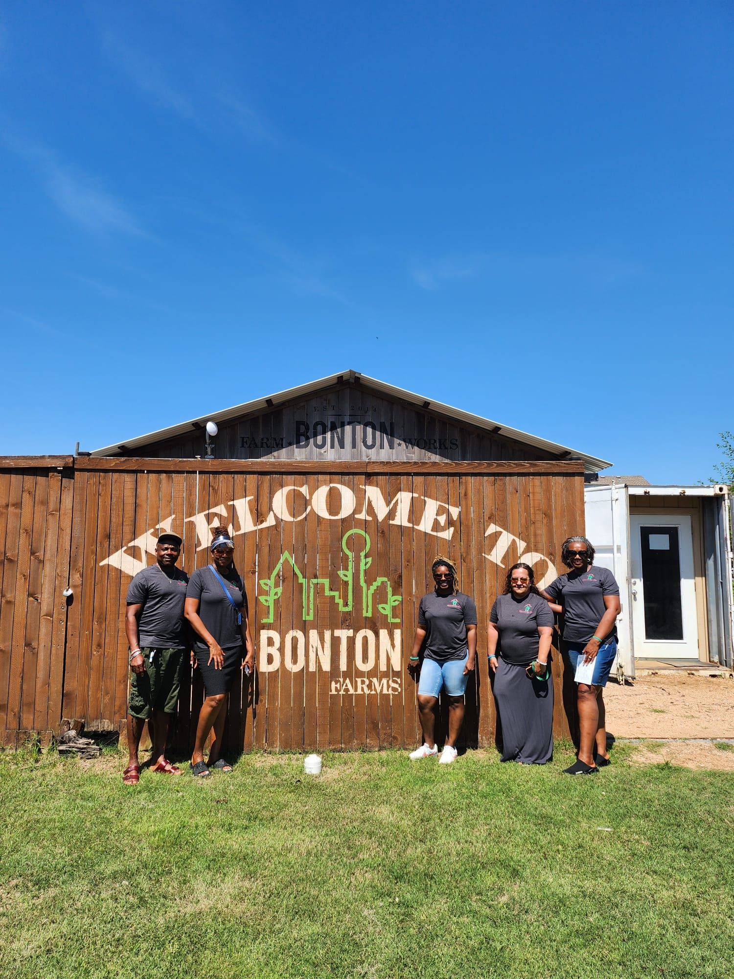 A group of women are standing in front of a wooden building.