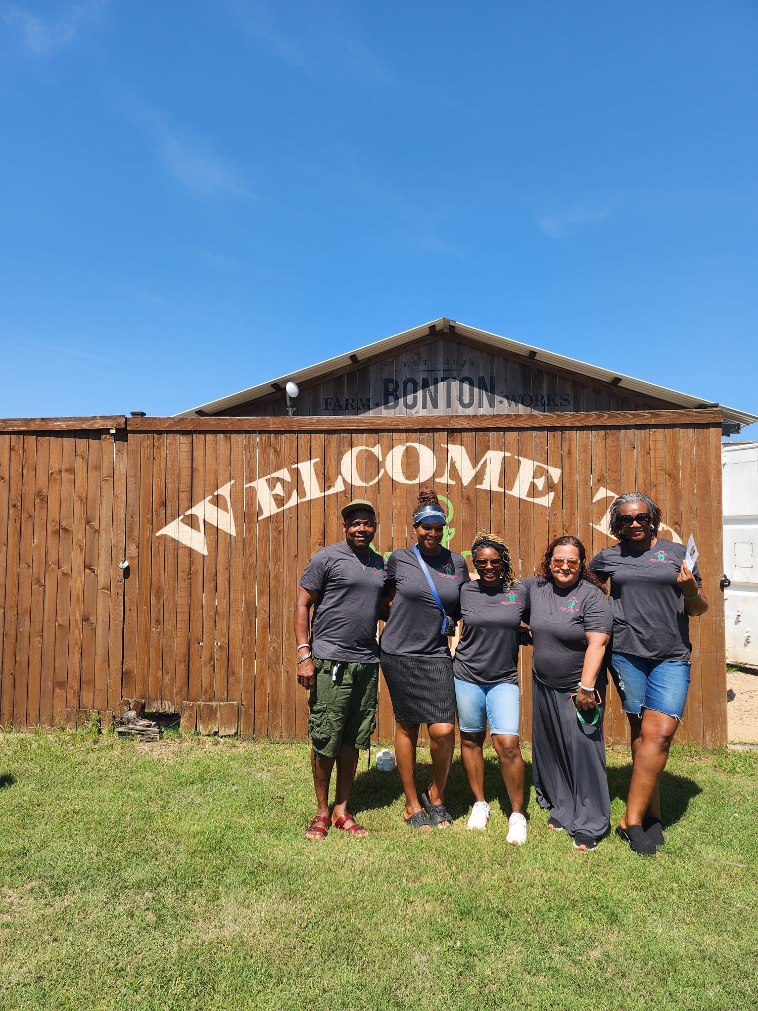 A group of people are posing for a picture in front of a welcome sign.