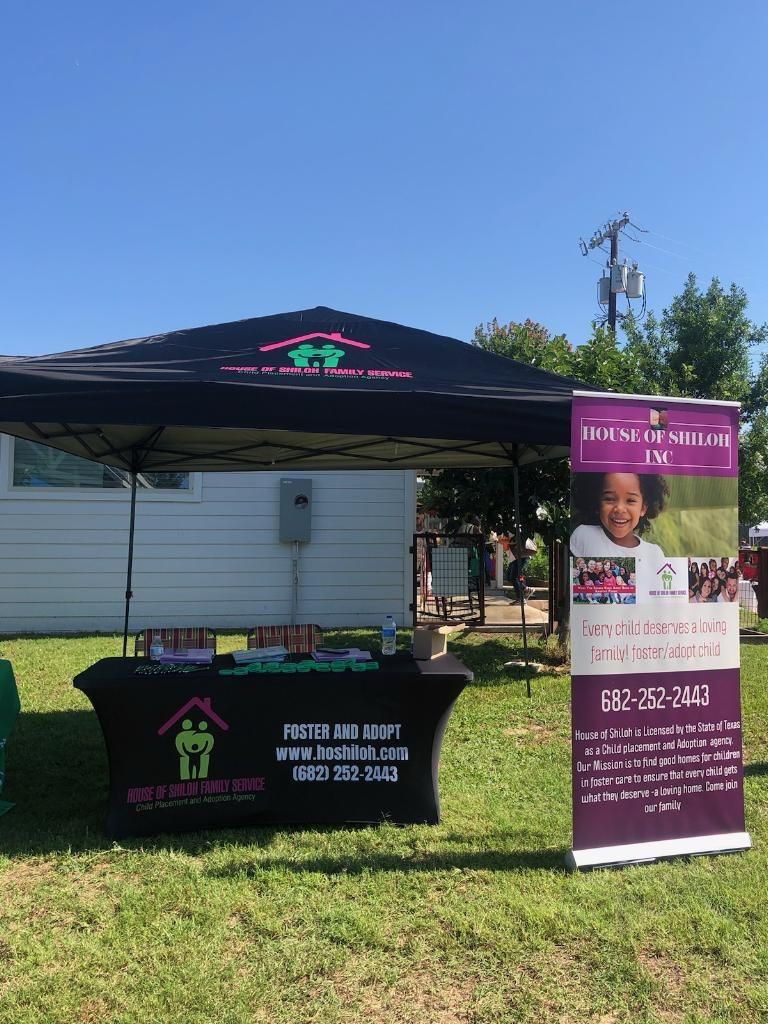A tent is sitting in the middle of a grassy field next to a table.