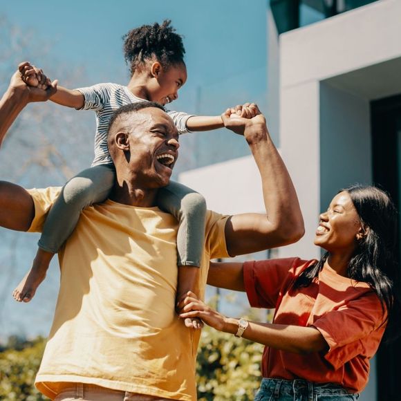 A man is carrying a little girl on his shoulders.