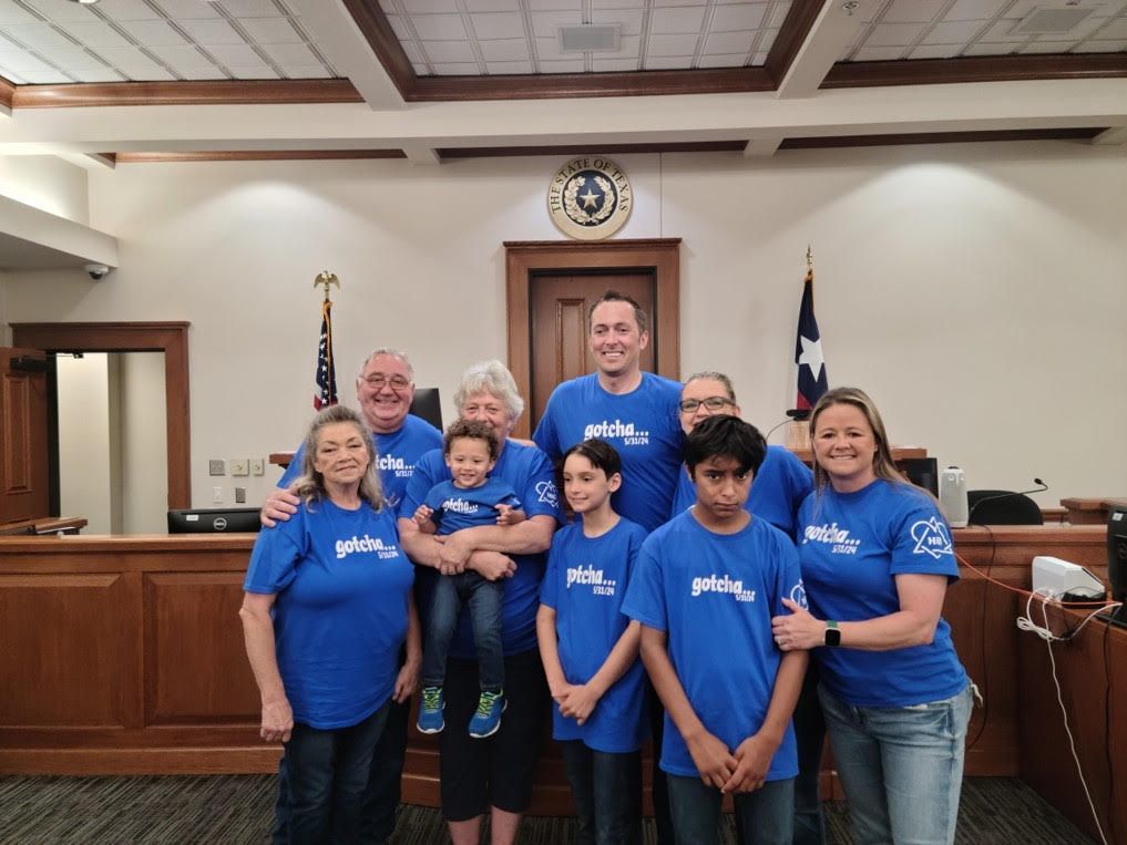 A group of people wearing blue shirts are posing for a picture in a courtroom.