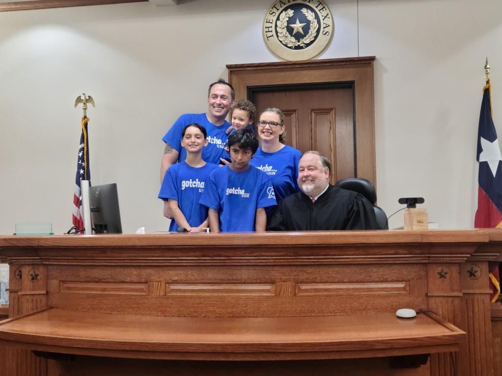 A group of people are posing for a picture in front of a judge in a courtroom.
