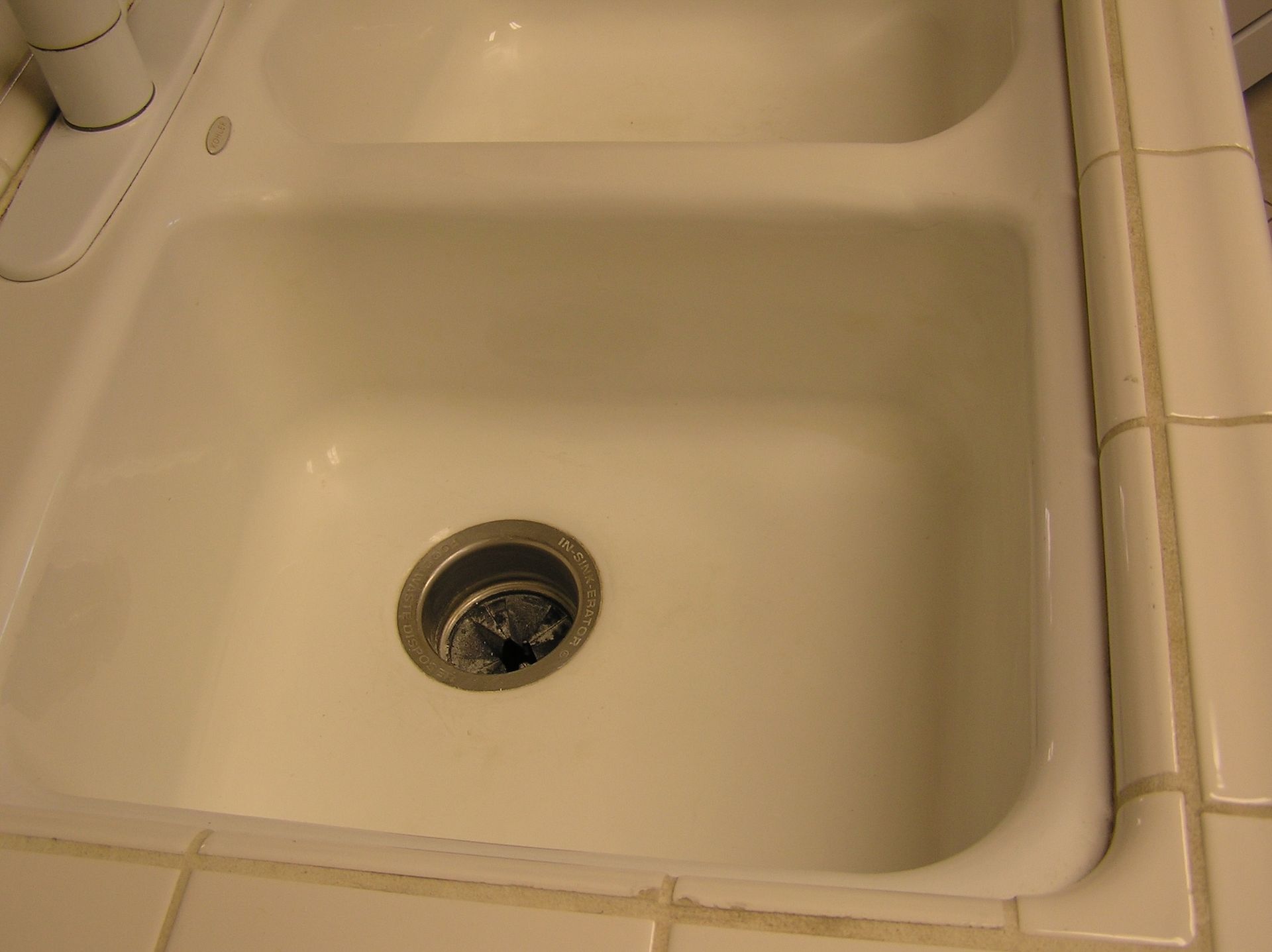 White kitchen sink with a double basin and a drain.
