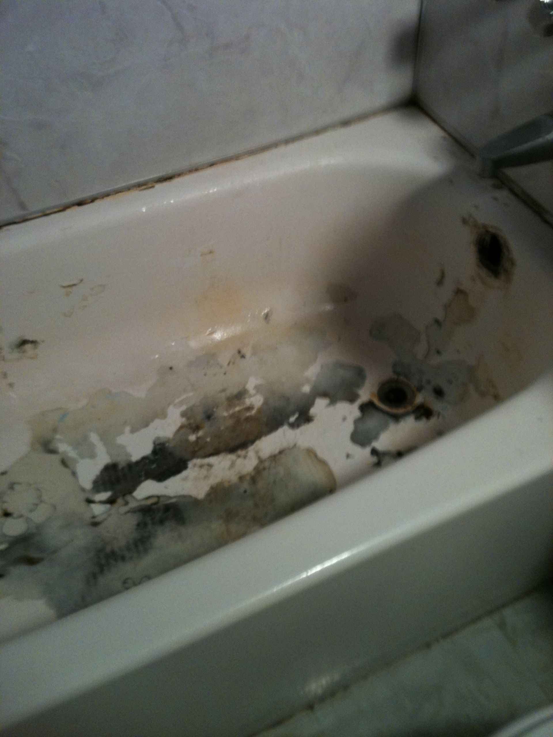 Dirty, stained bathtub with dark mildew.