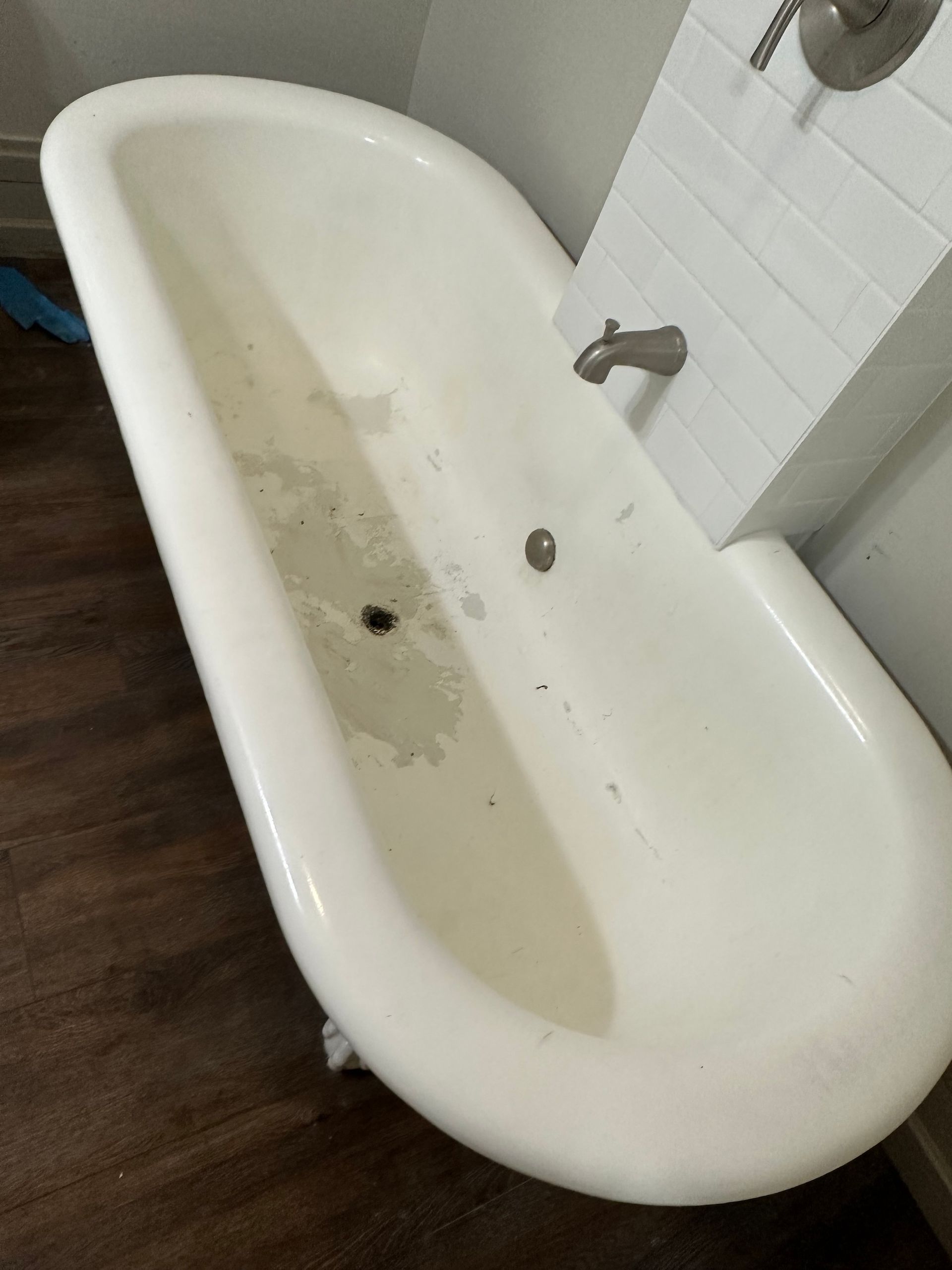 White, vintage bathtub in a bathroom with dark wooden flooring.