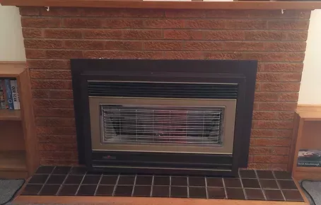 before of a fireplace in a living room with a brick wall and a wooden mantle 