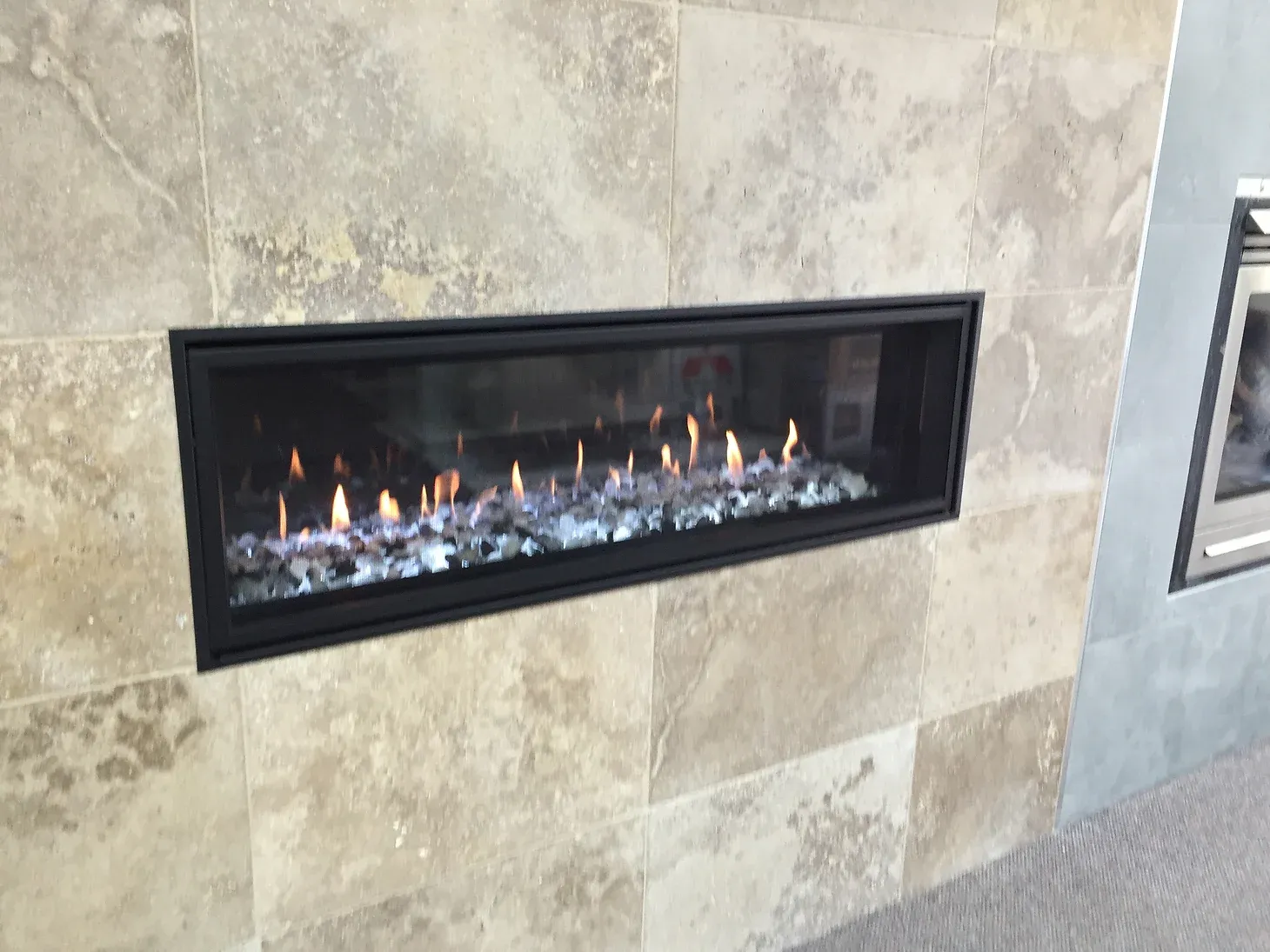 narrow gas fireplace built into tiled wall 