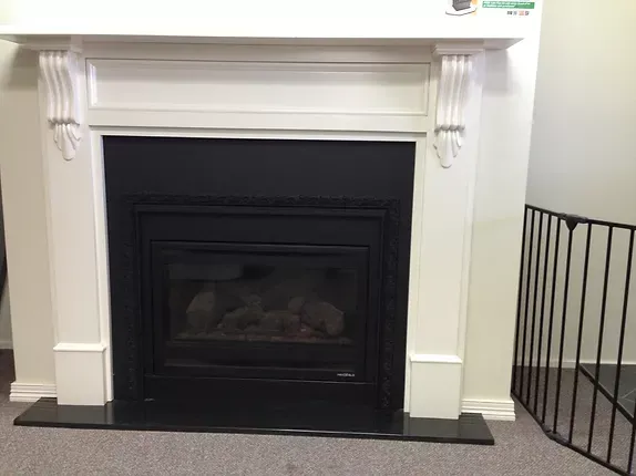 a fireplace with a black surround and a white mantle