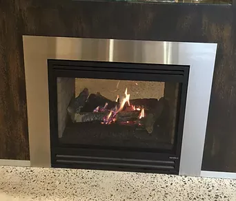 a fireplace installed by dwr services with a stainless steel trim is filled with logs and fire .