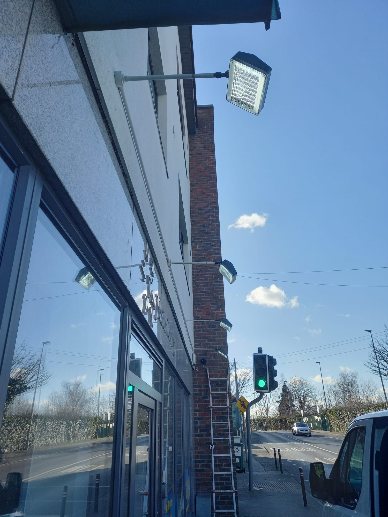 A ladder is hanging from the side of a building next to a traffic light.