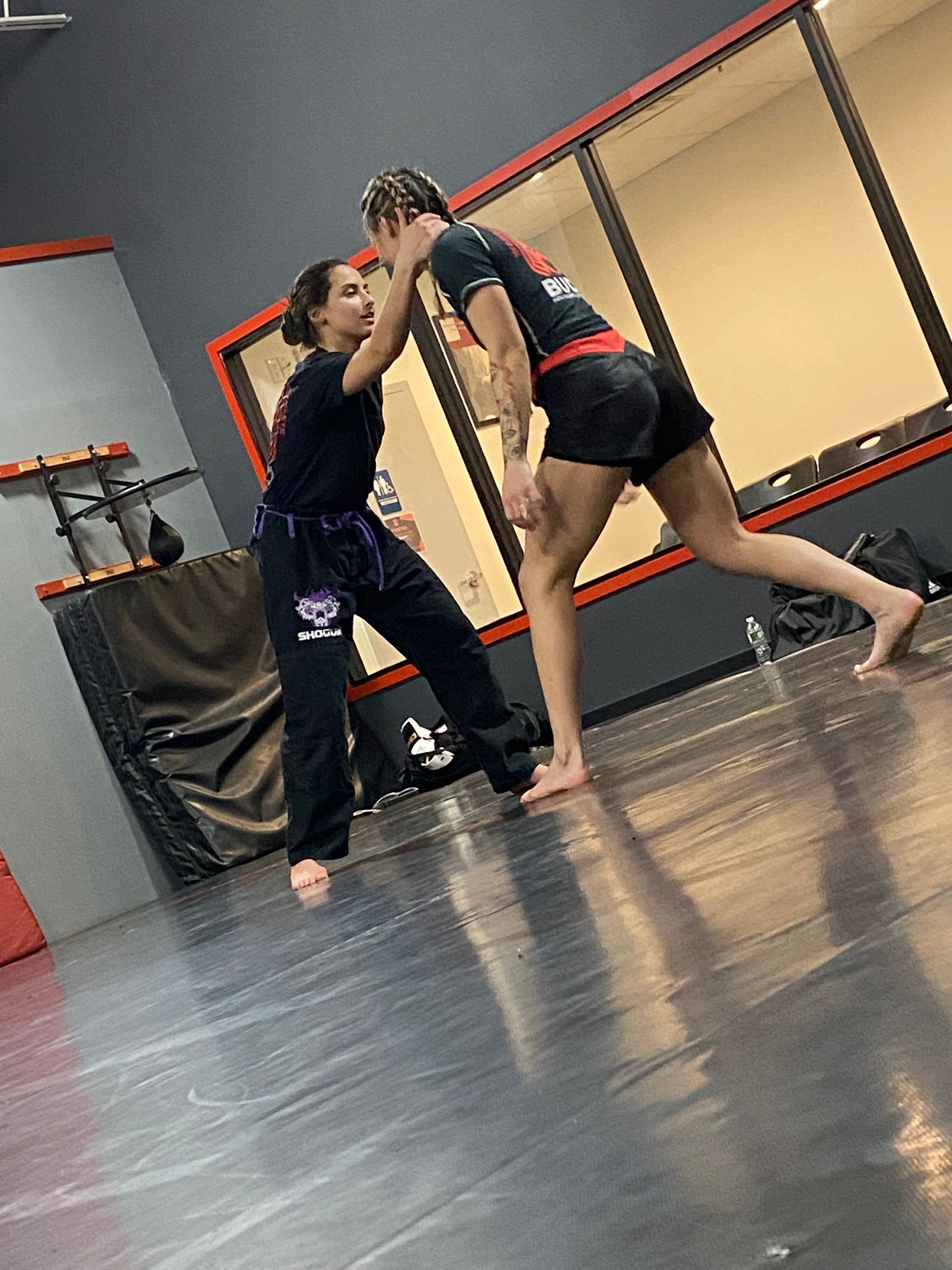 two women are wrestling on a mat in a gym .