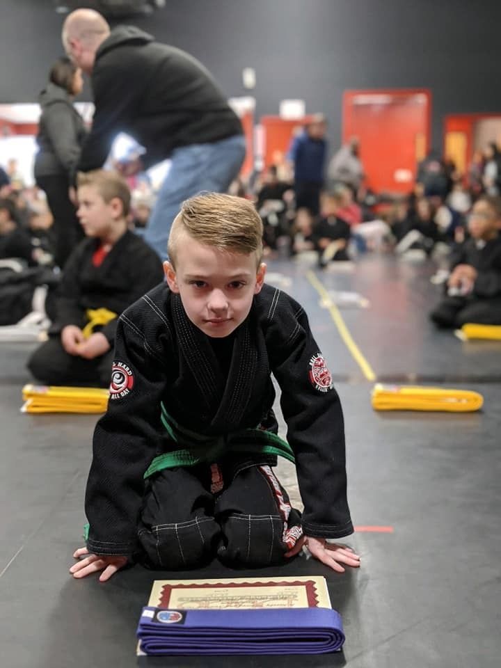 a young boy in a karate uniform is kneeling on the floor