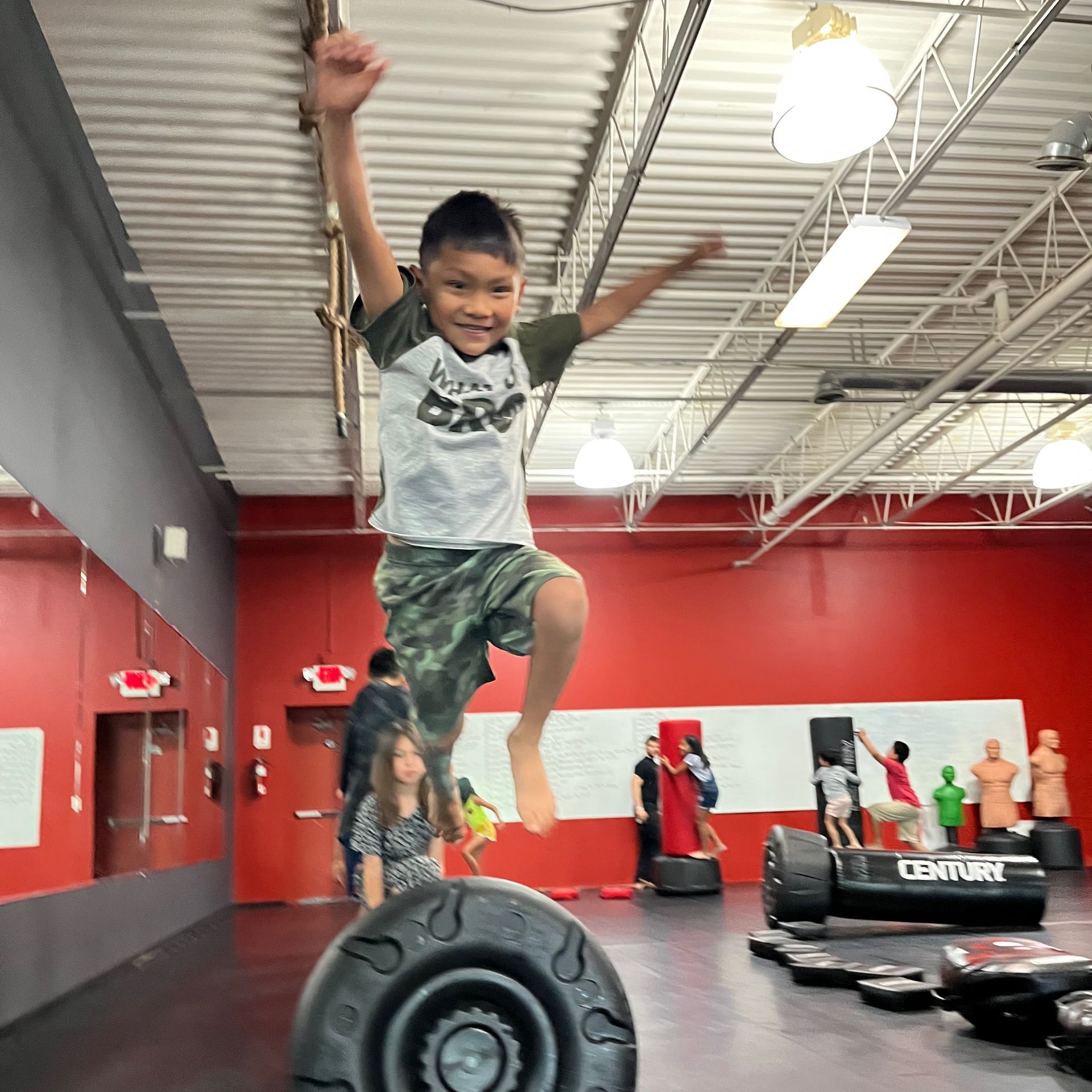 a young boy is standing on a tire in a gym .