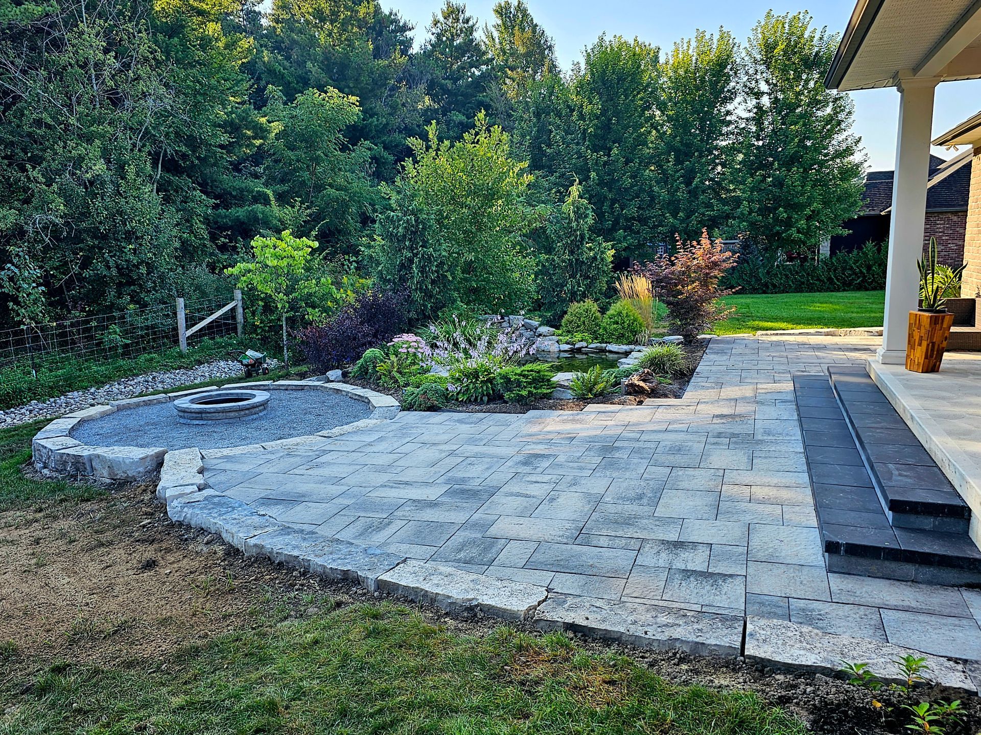 a patio with a fire pit in the middle of it in a backyard .