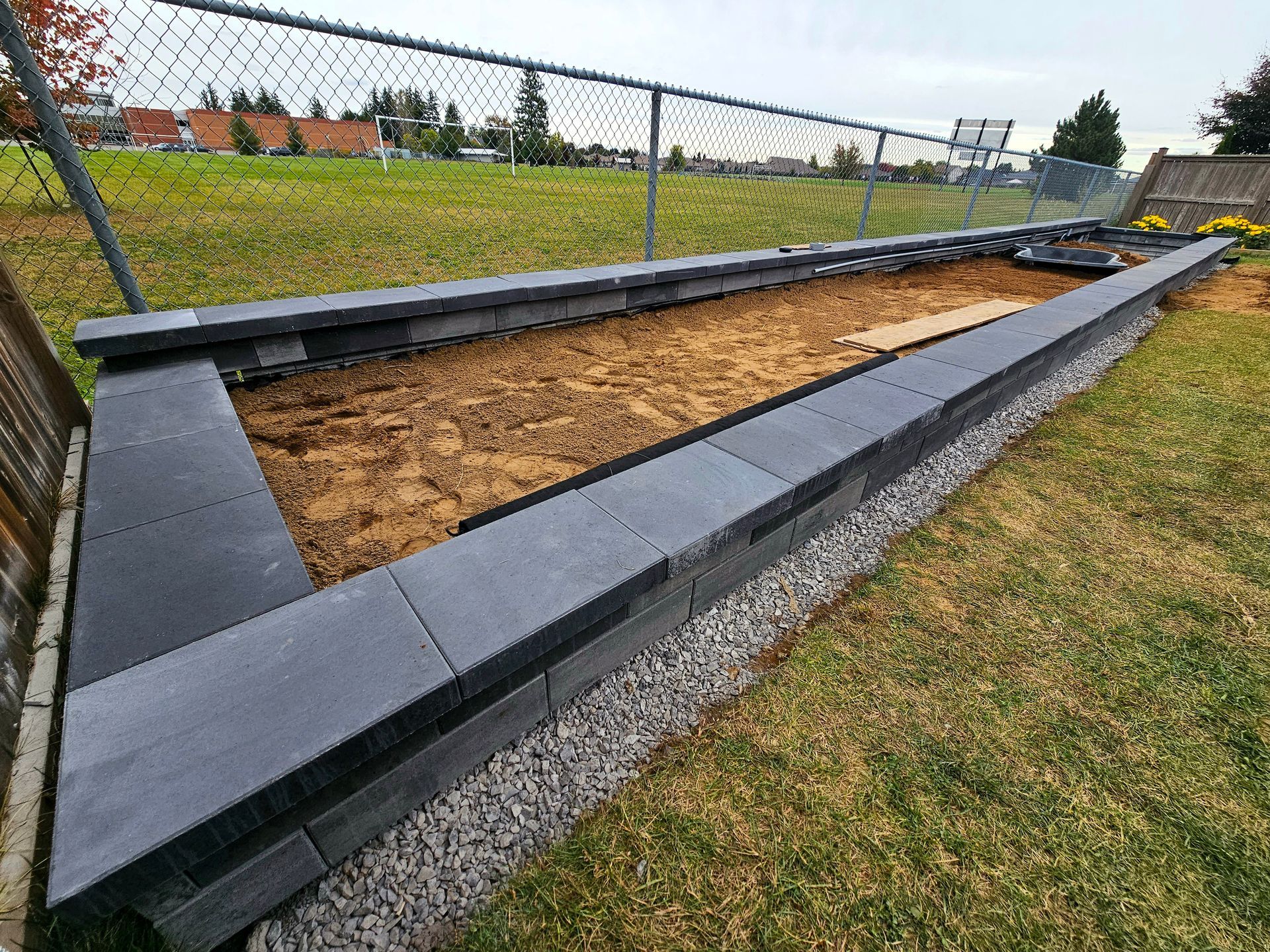 a fenced in area with a brick wall and gravel .