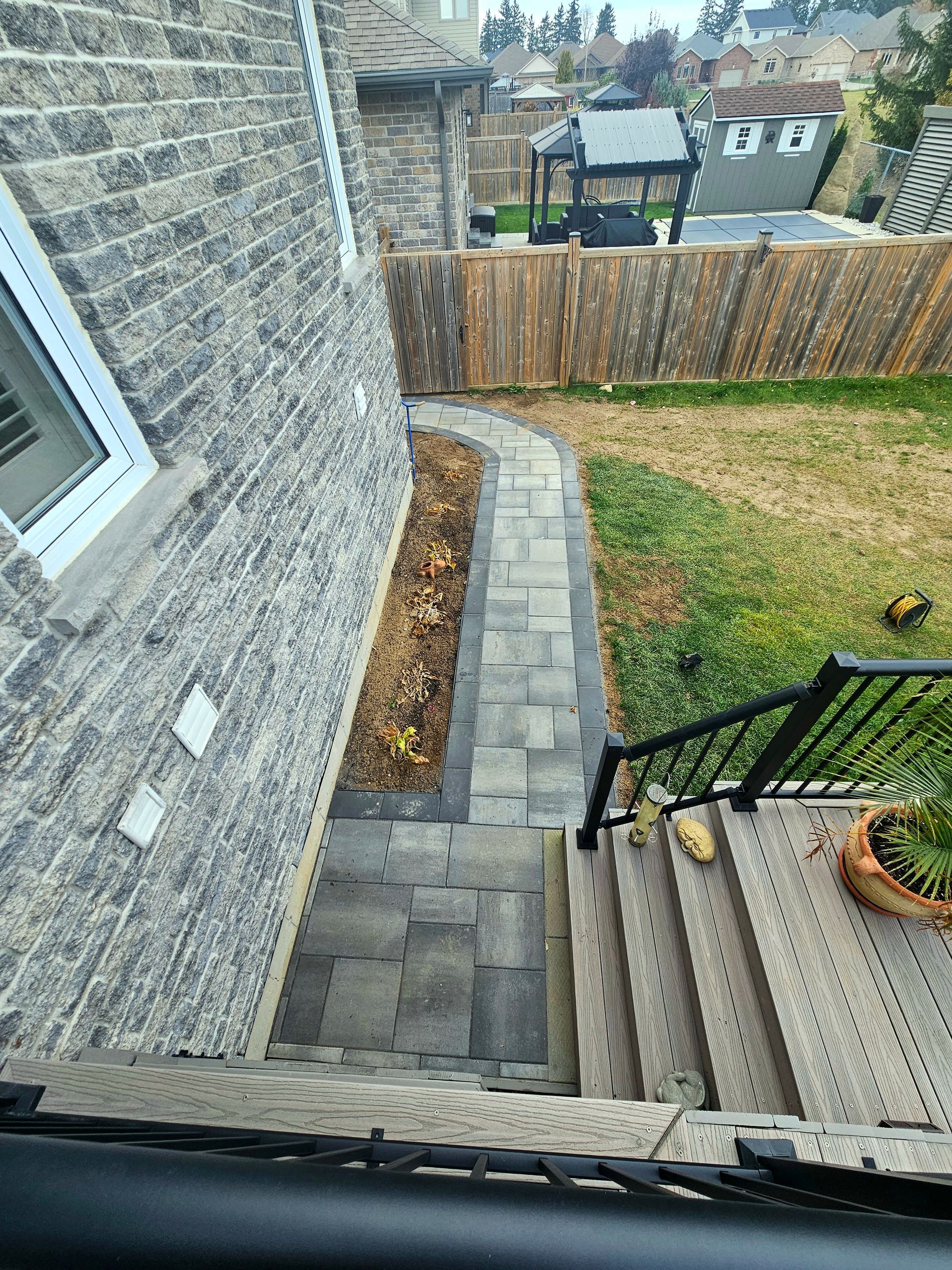 a view of a sidewalk and stairs from the back of a house .