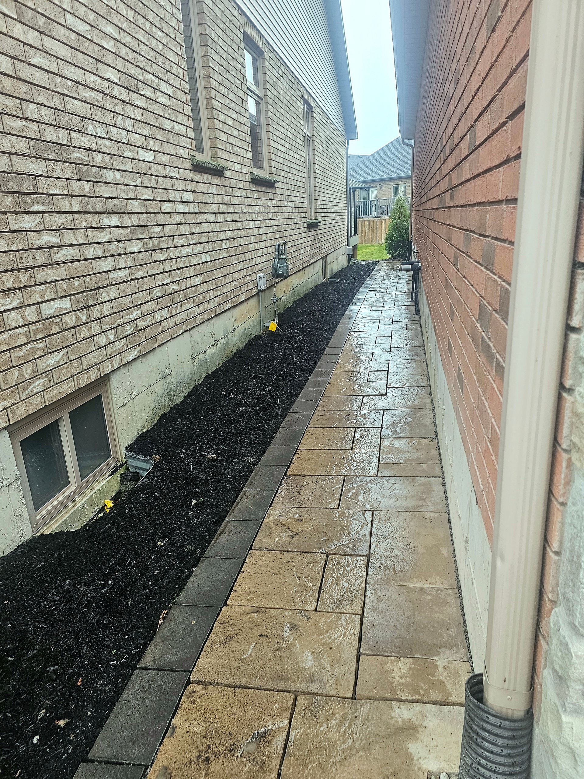 there is a sidewalk between two brick buildings .