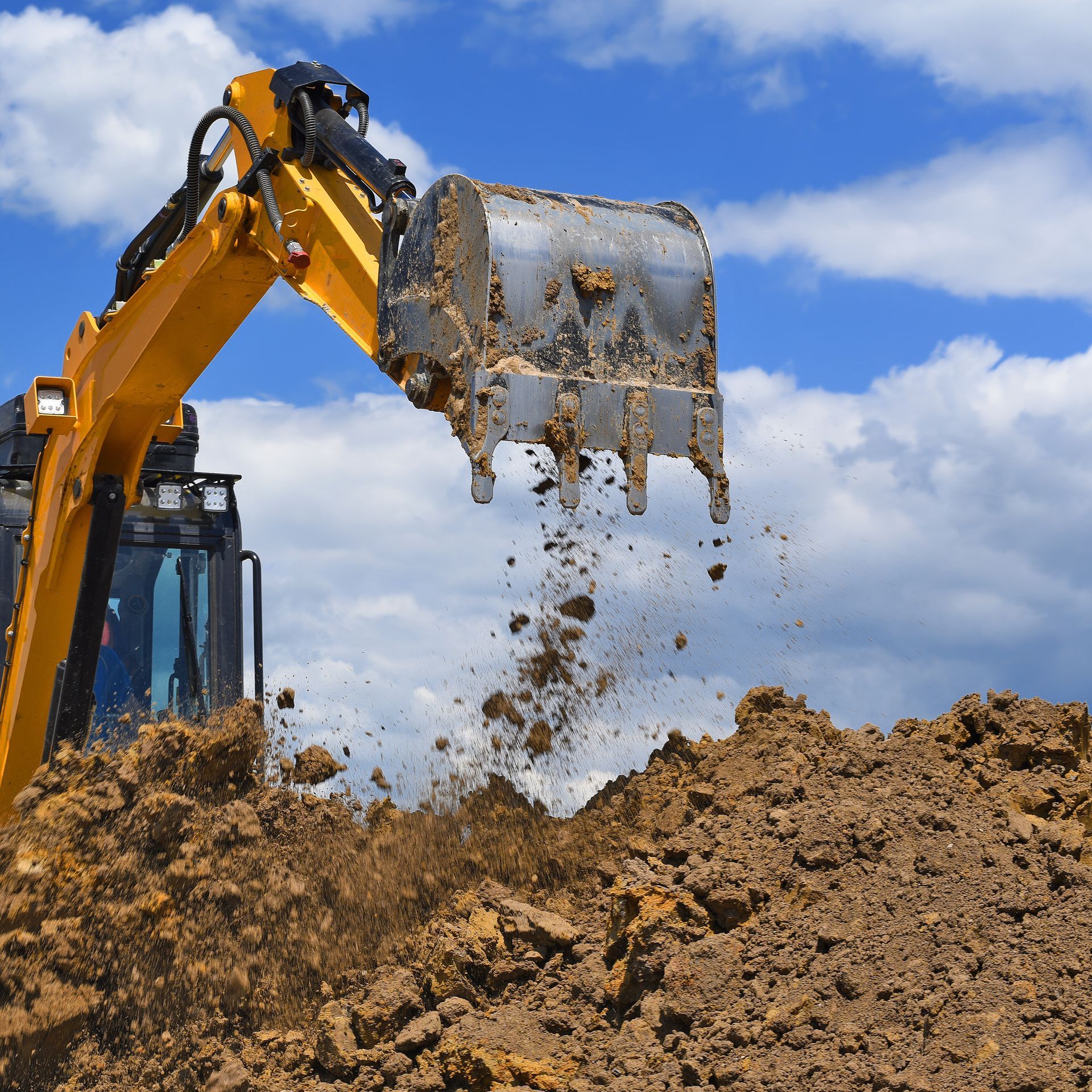 a yellow excavator is digging a pile of dirt