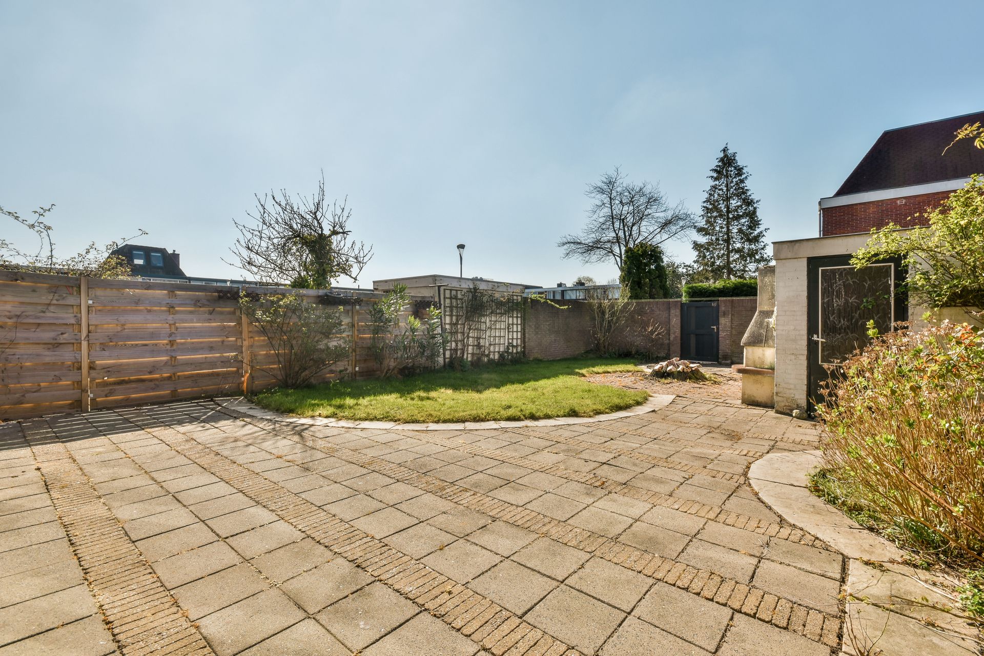 There is a brick driveway in the backyard of a house.