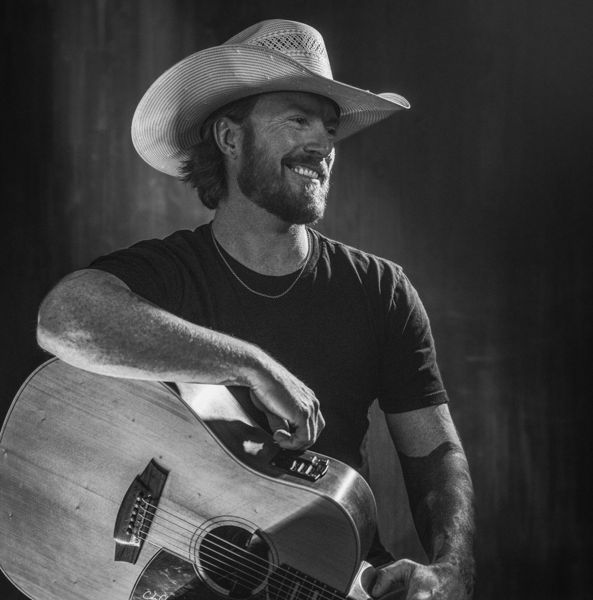 A man in a cowboy hat is holding a guitar