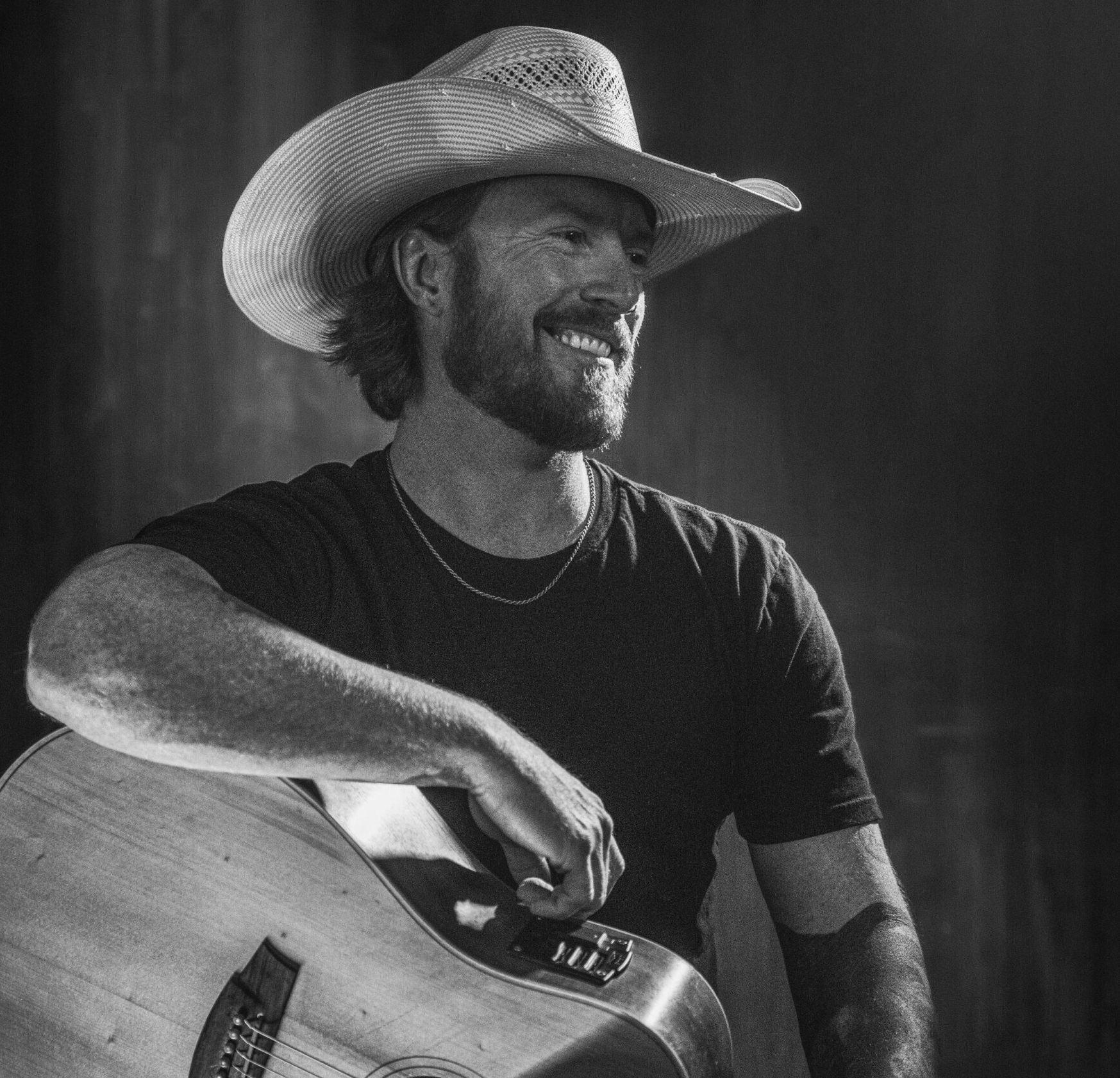 A man in a cowboy hat is playing an acoustic guitar.