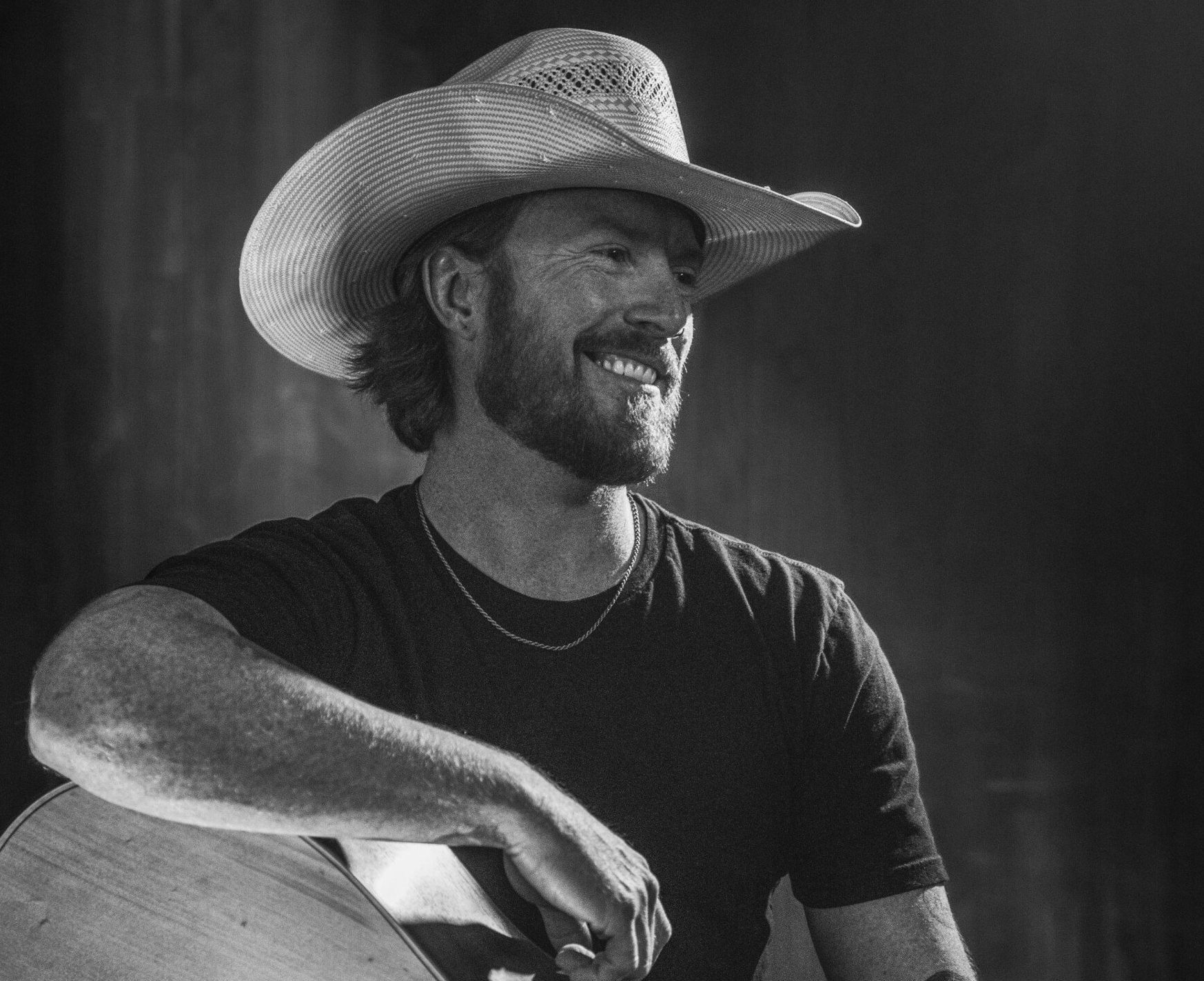 A man in a cowboy hat is playing an acoustic guitar.