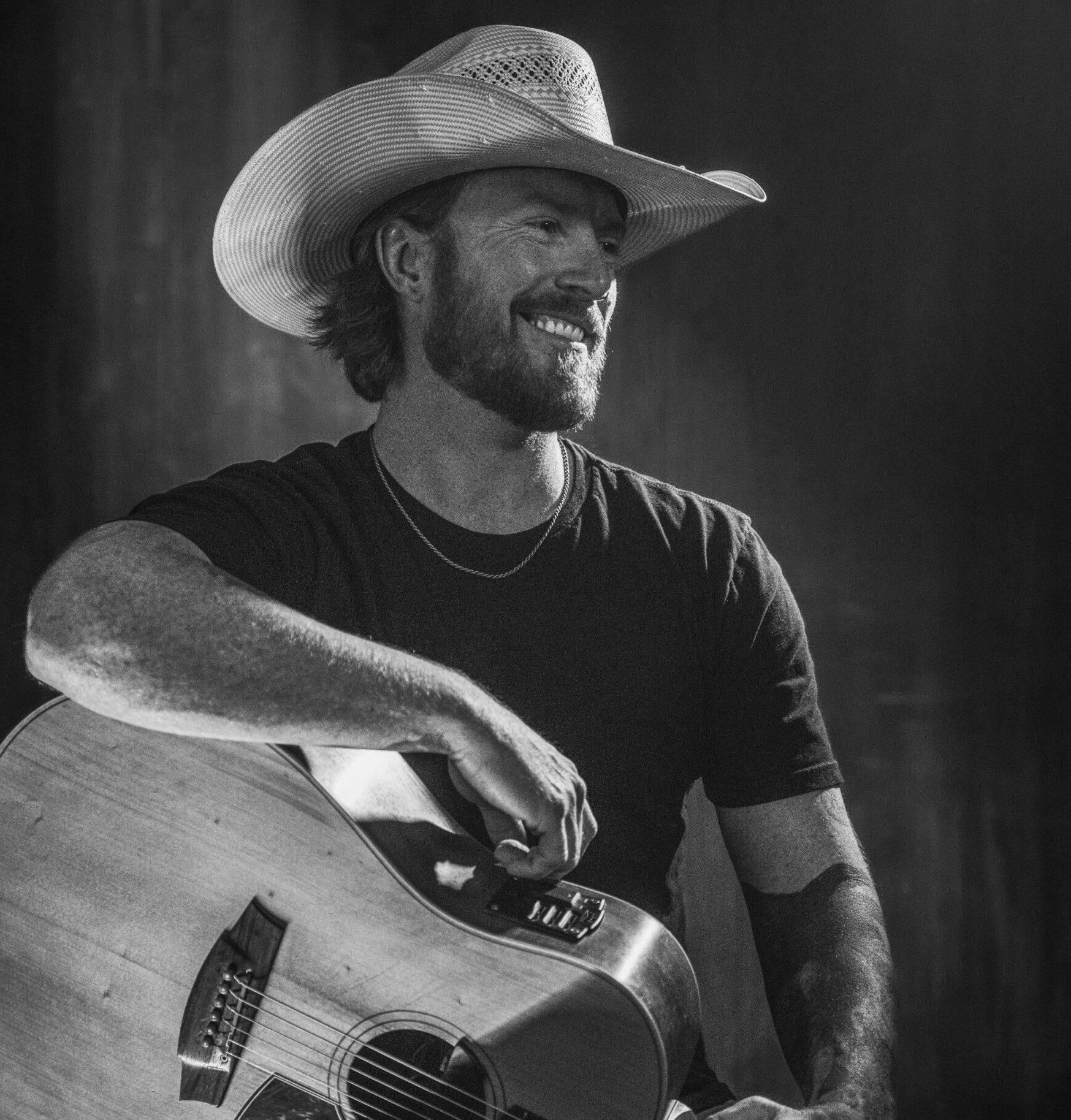 A man in a cowboy hat is playing an acoustic guitar.