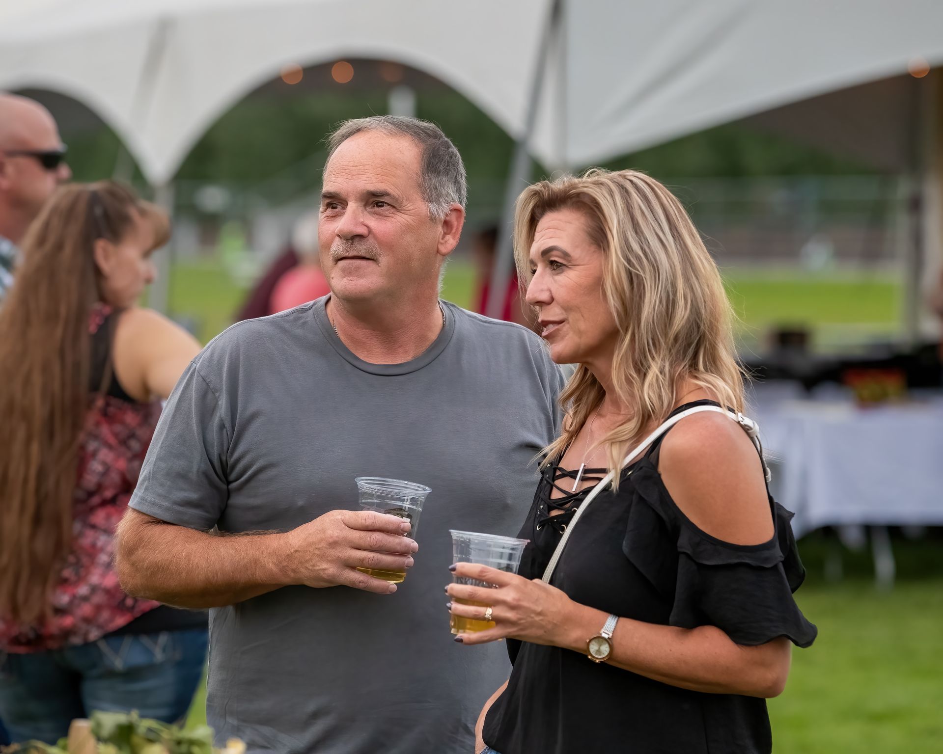 A man and a woman are standing next to each other holding drinks.