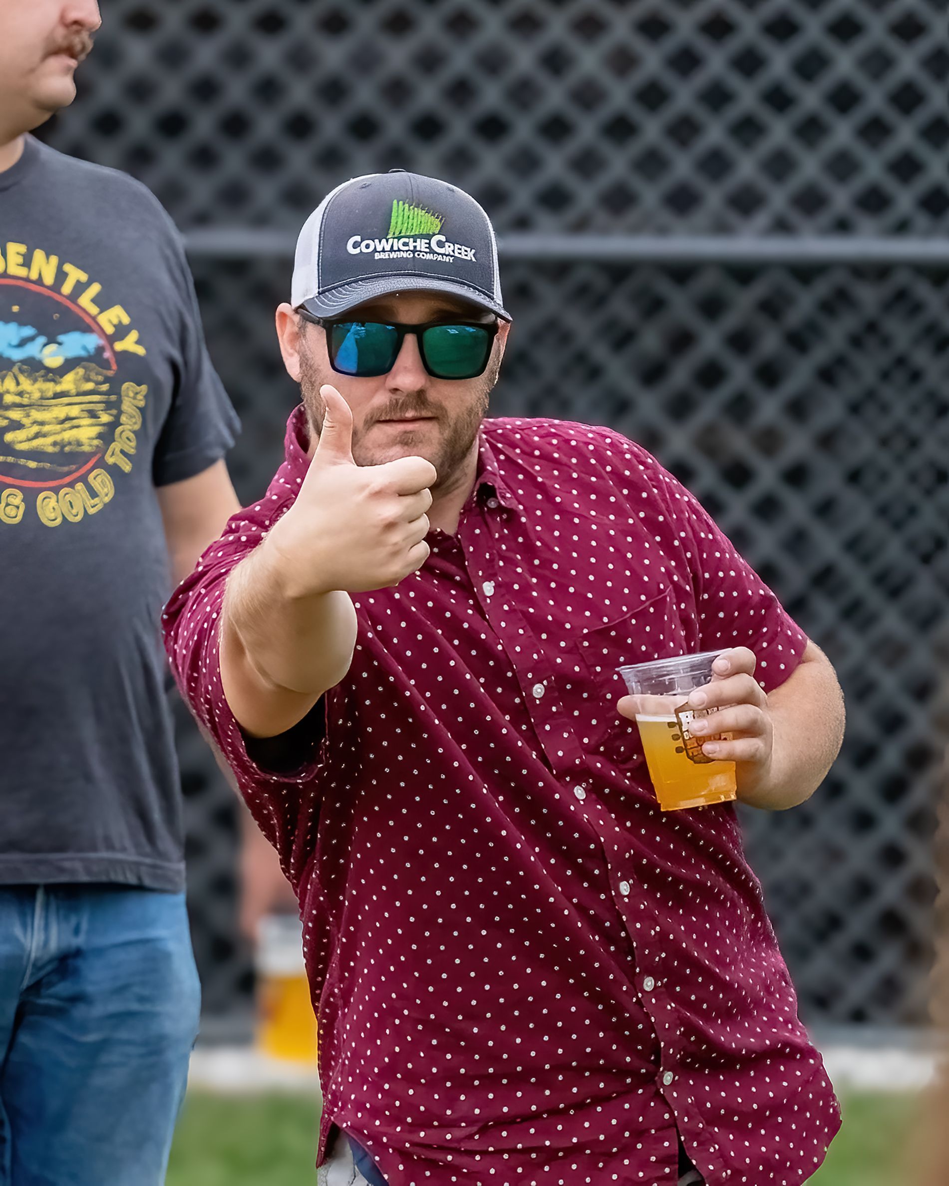 A man in a bentley shirt is giving a thumbs up