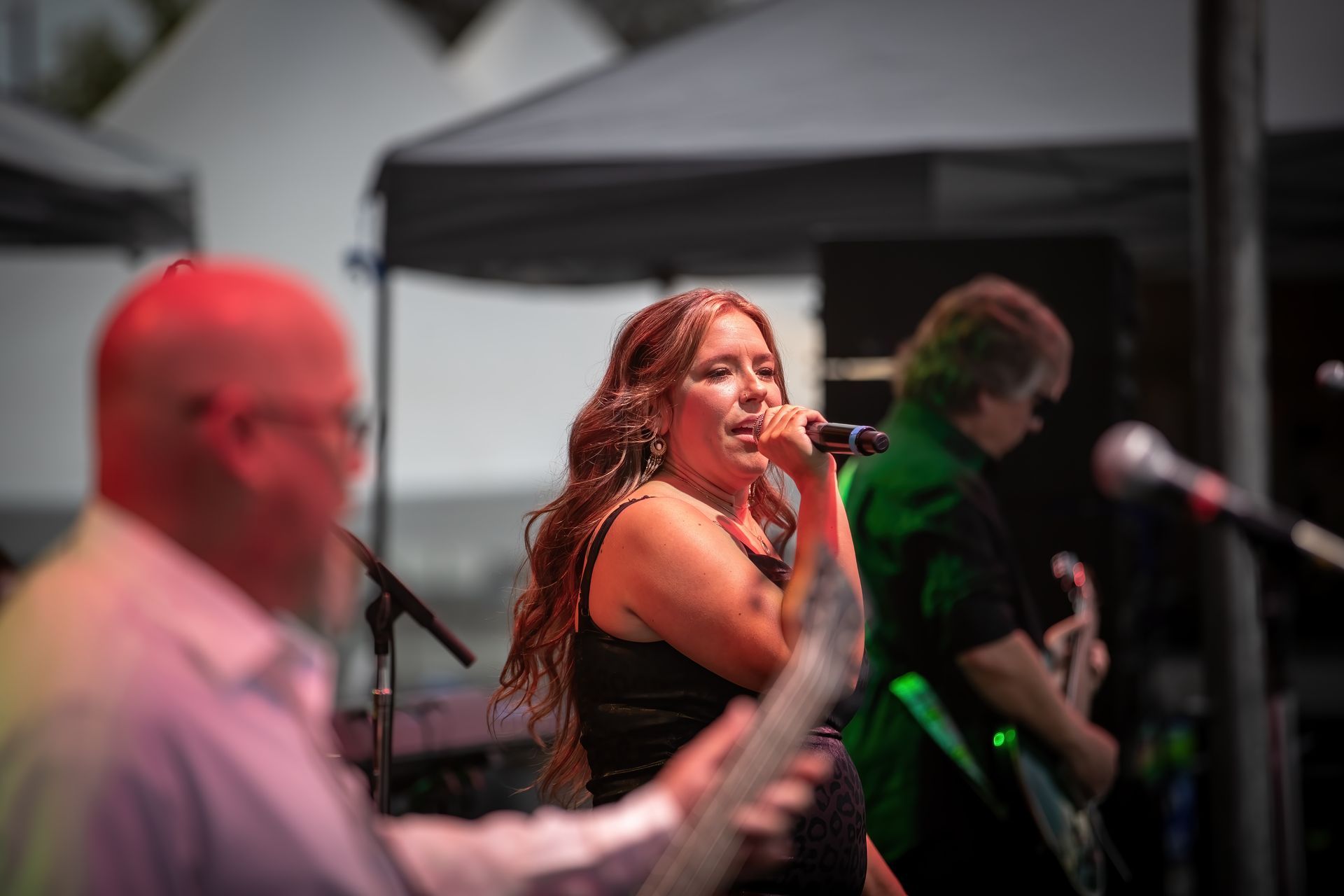 A woman is singing into a microphone on a stage while a man plays a guitar.
