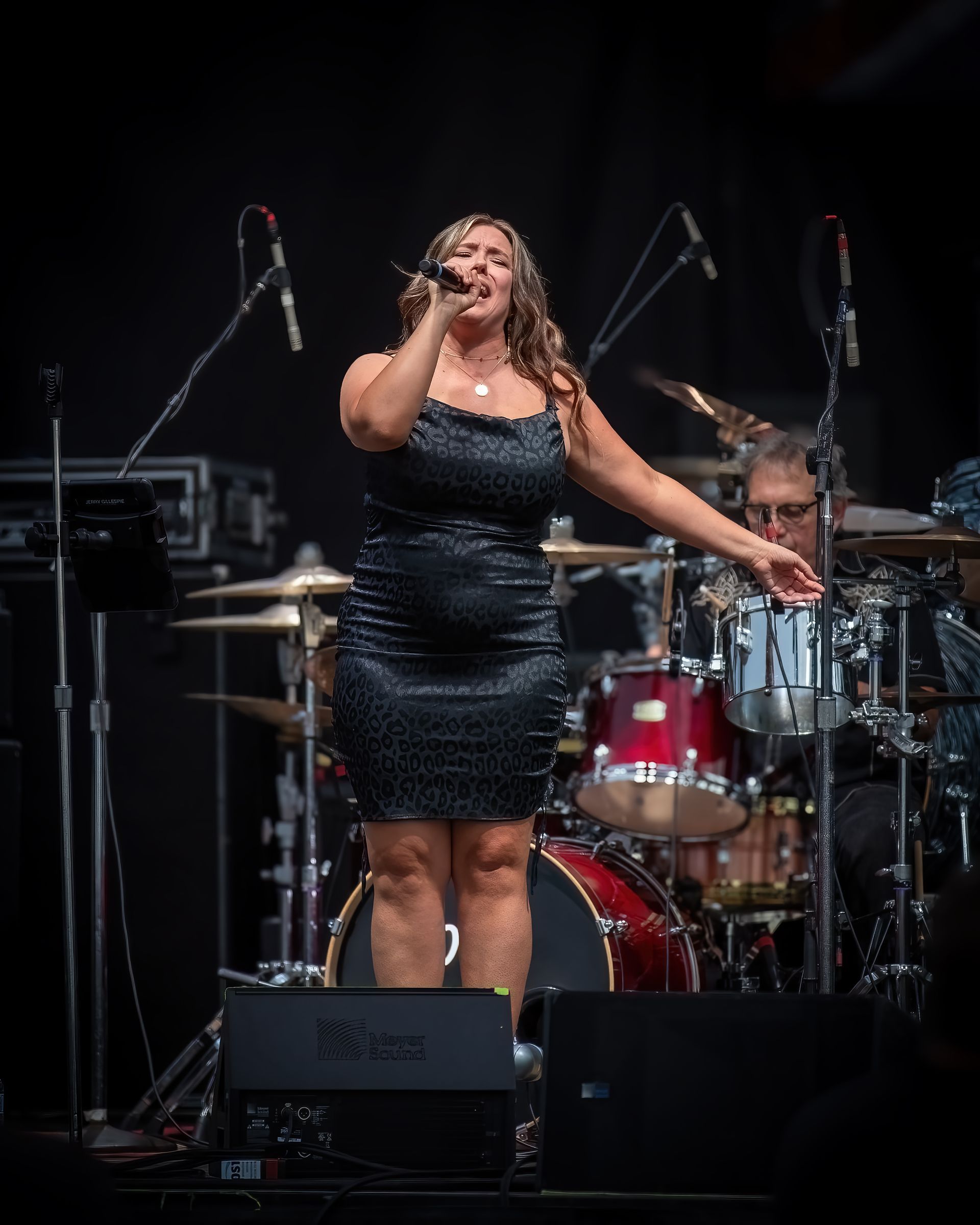 A woman in a black dress is singing into a microphone on a stage.