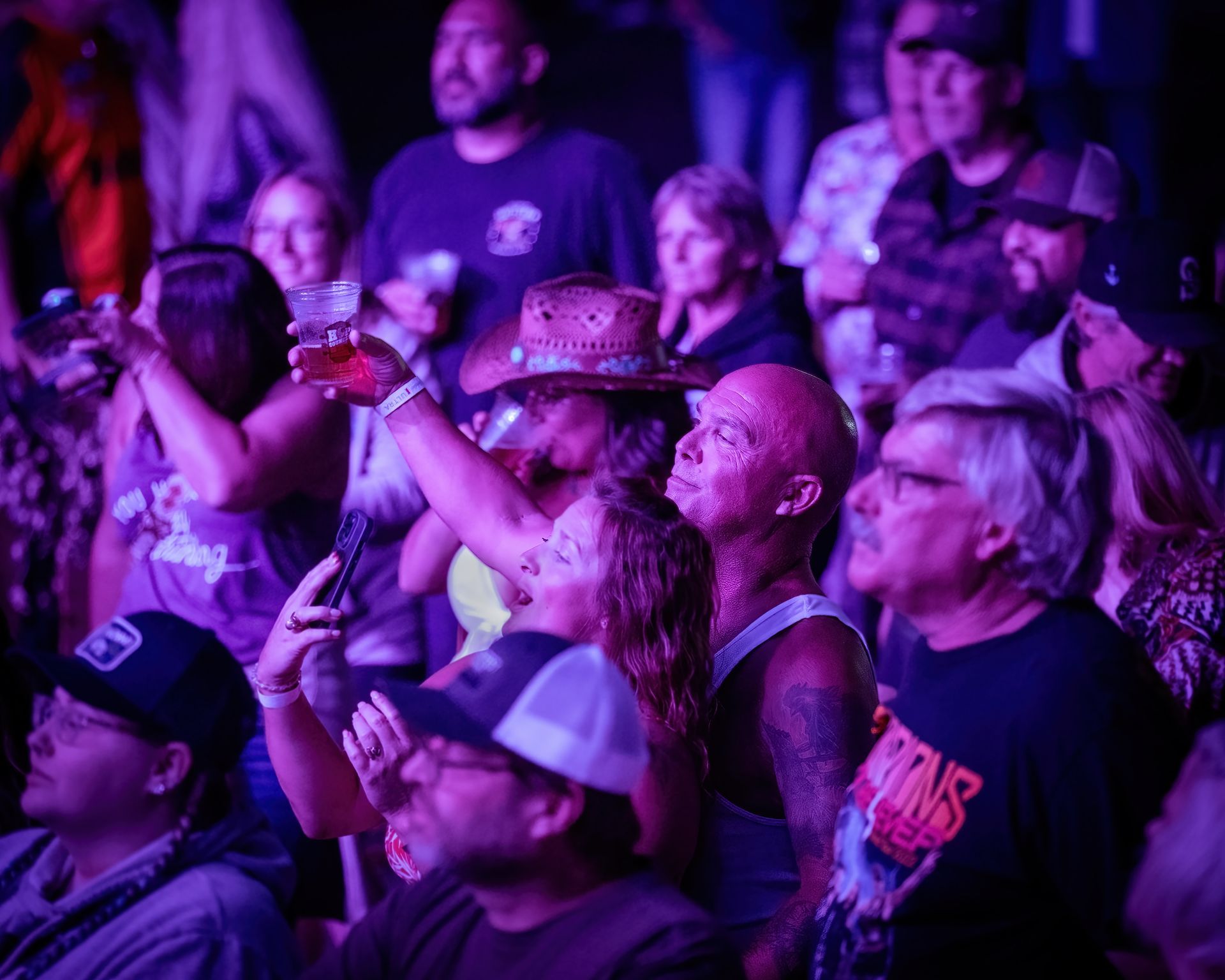 A crowd of people are sitting in a dark room watching a concert.