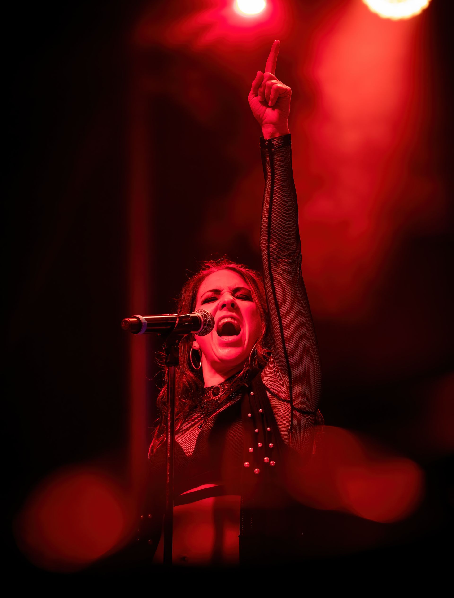 A woman is singing into a microphone with her hand in the air.
