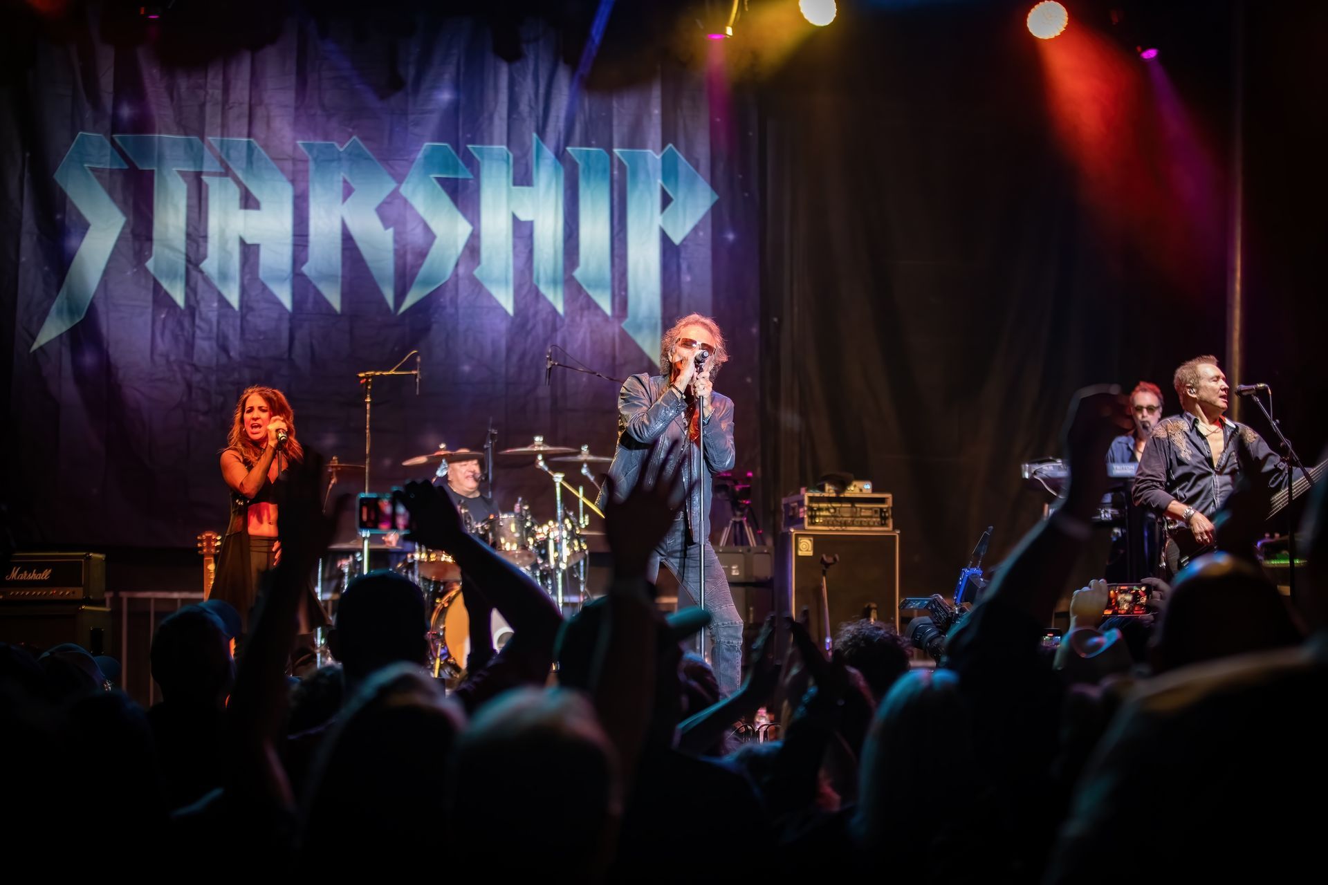 A group of people are standing on a stage in front of a sign that says starship.