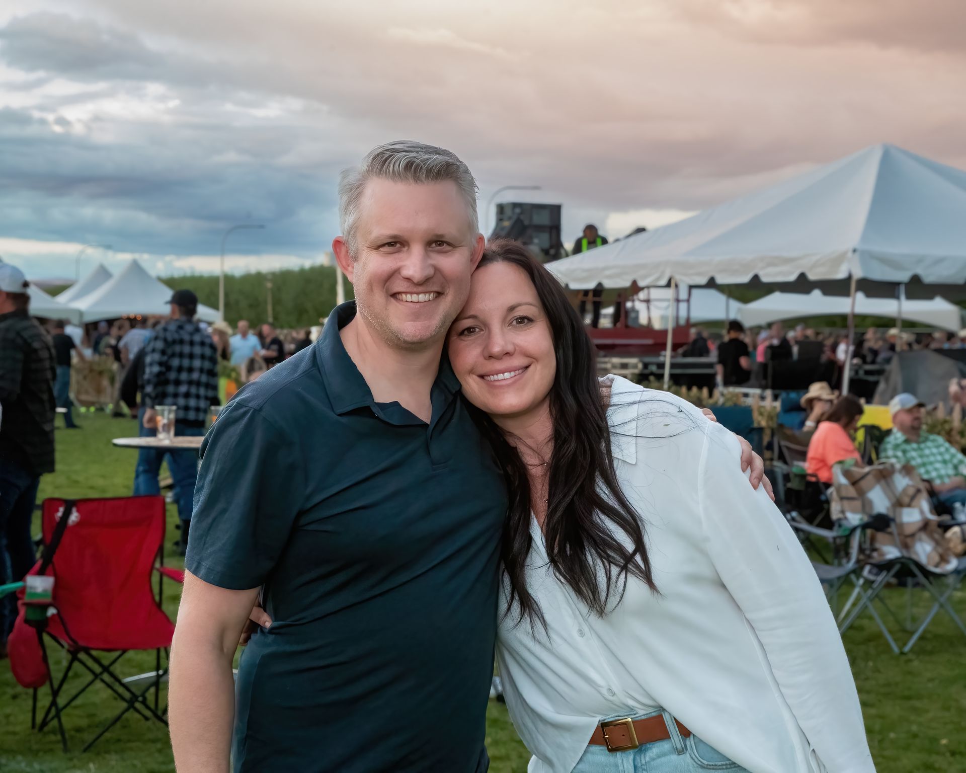 A man and a woman are posing for a picture in a field.