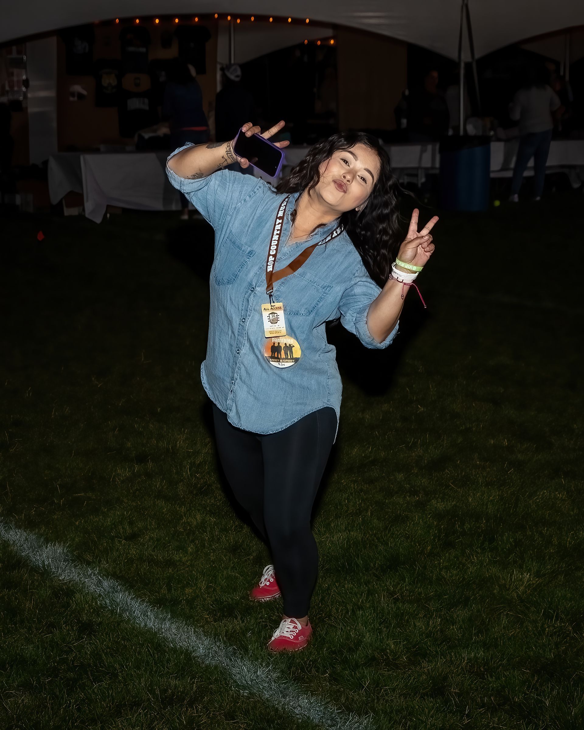 A woman in a denim shirt is giving a peace sign
