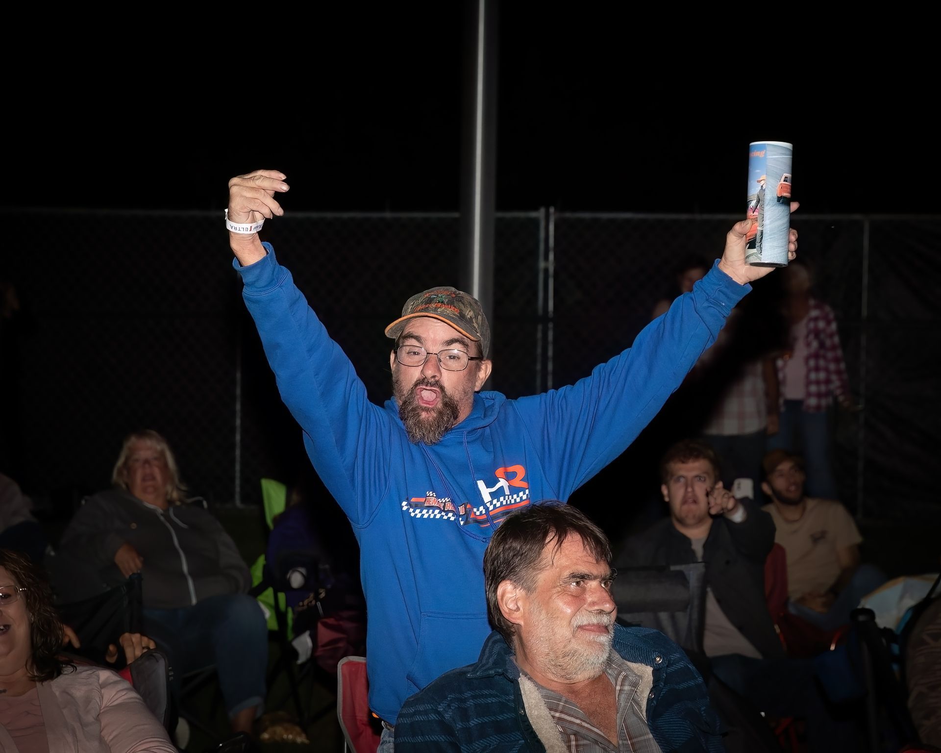 A man in a blue sweatshirt is holding a can of beer in his hand.