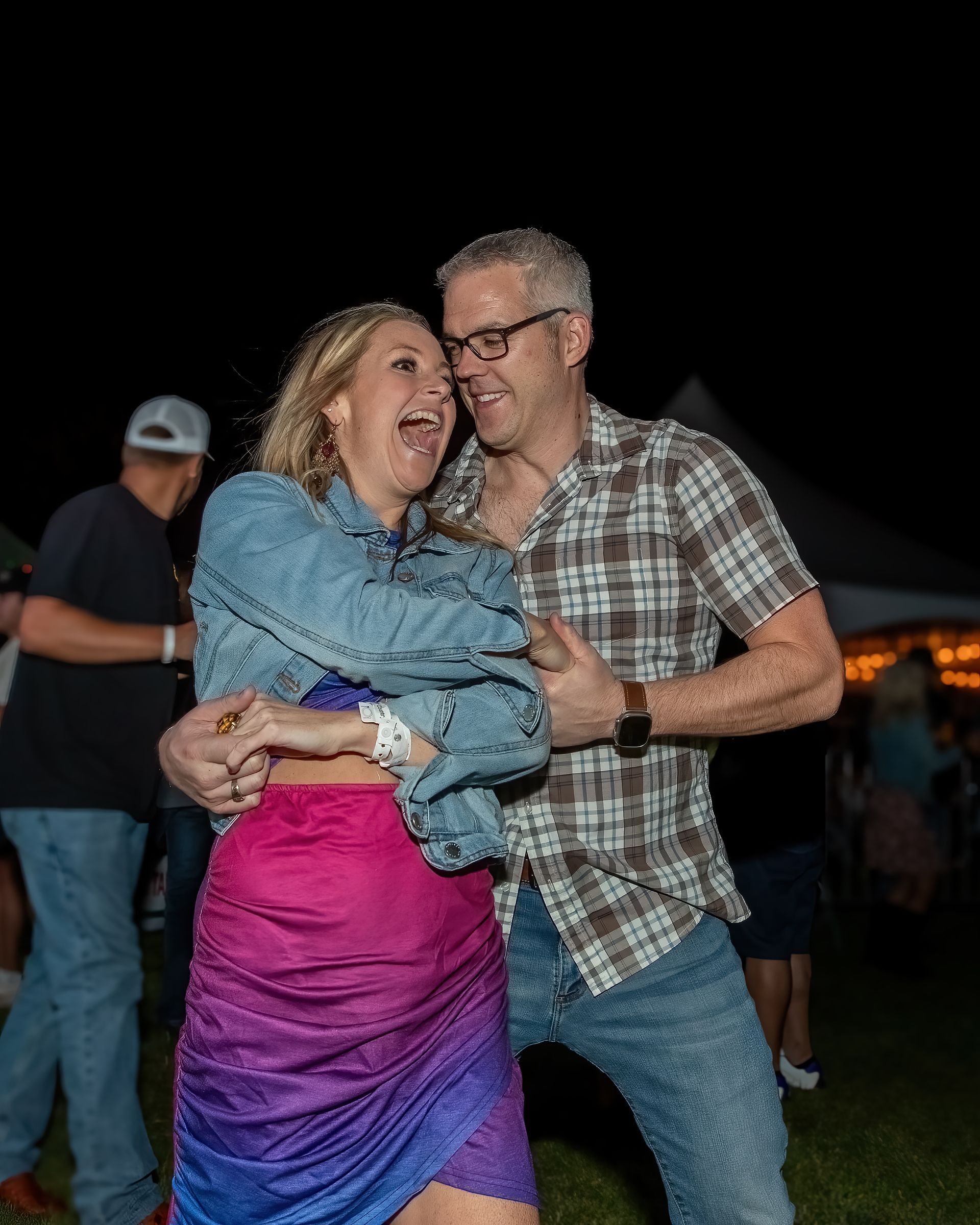A man and a woman are dancing together in a field at night.