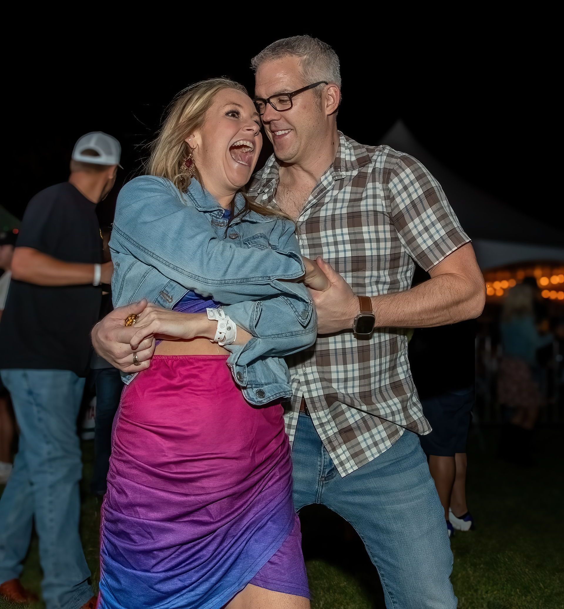 A man and a woman are dancing together in a field at night.